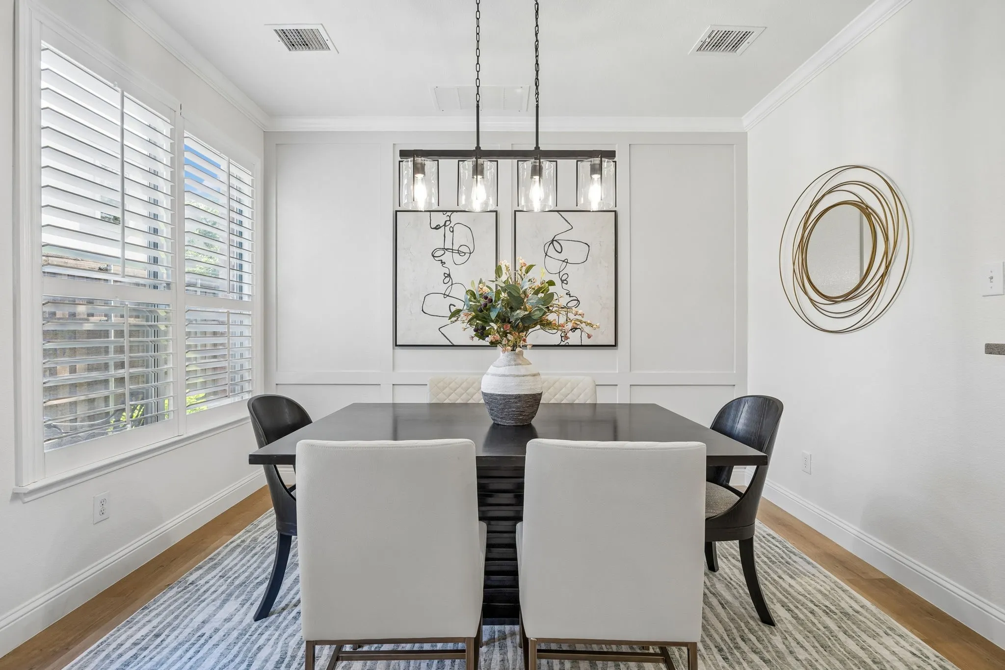Dining area featuring wood-finish flooring, white plantation shutters, and crown molding