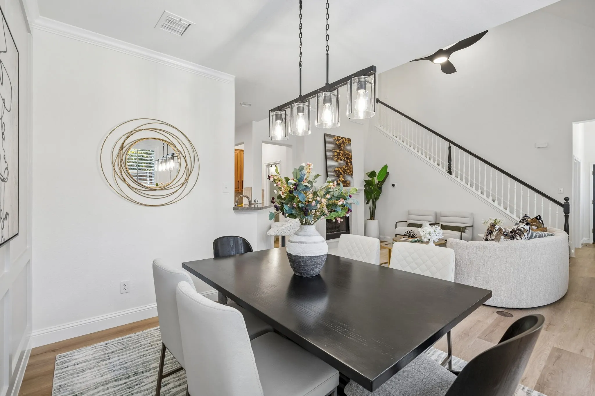 Formal dining space featuring a black rectangular table and a linear chandelier with clear glass shades