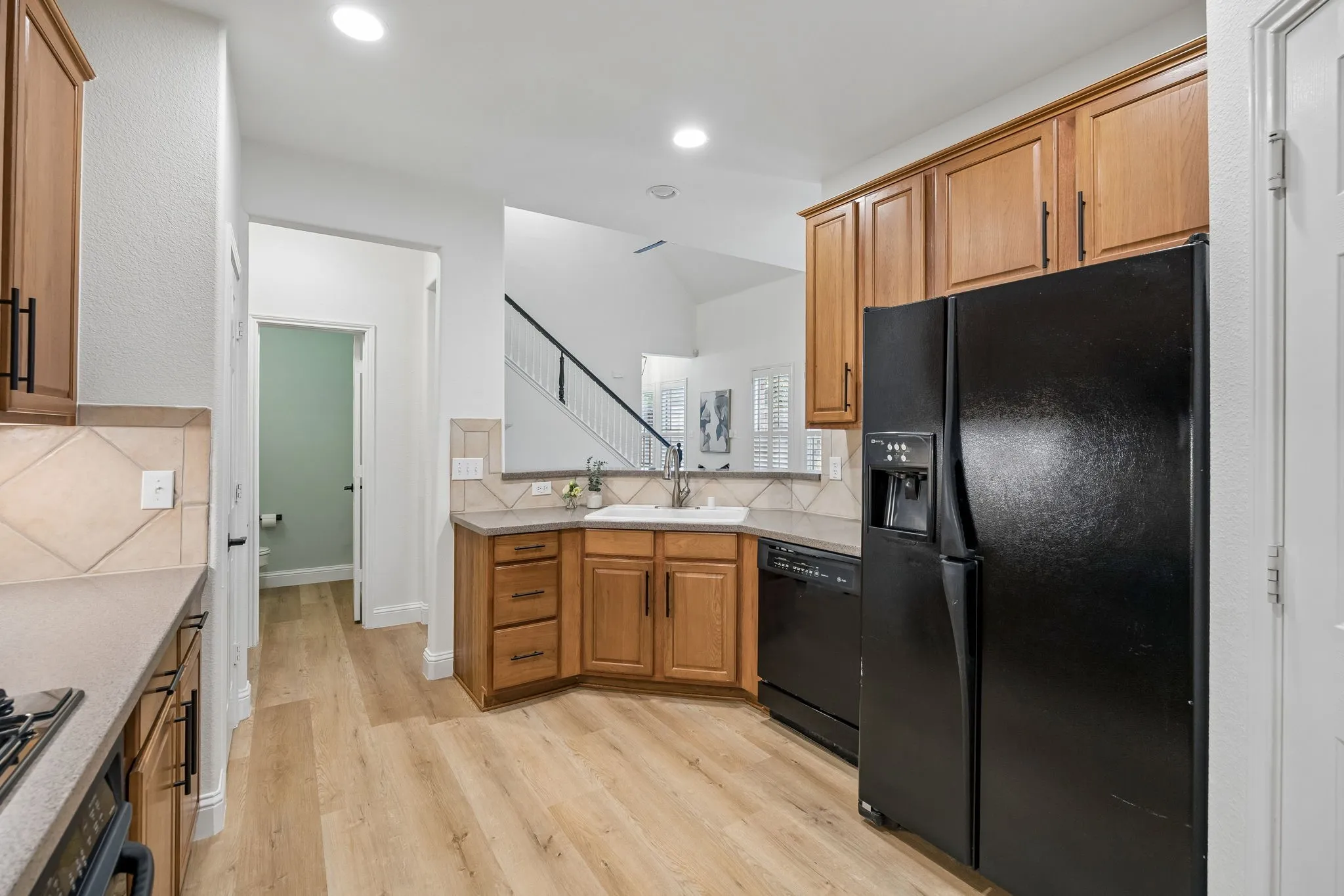 Kitchen featuring light wood-finish flooring, recessed lighting, medium-tone wood cabinetry, and a tile backsplash