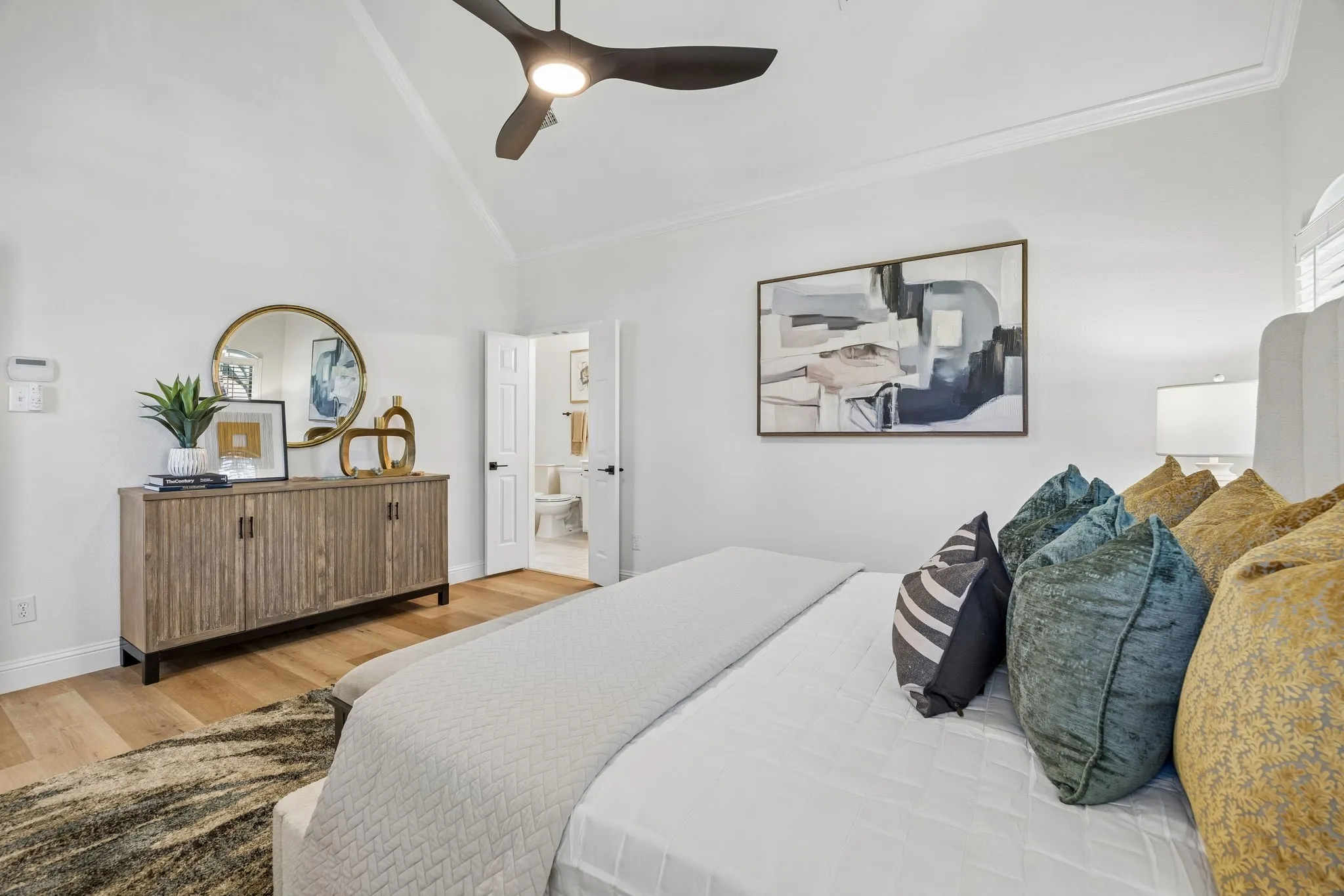 Vaulted ceiling with an illuminated ceiling fan, wood-finish flooring, white baseboards, and a white six-panel door