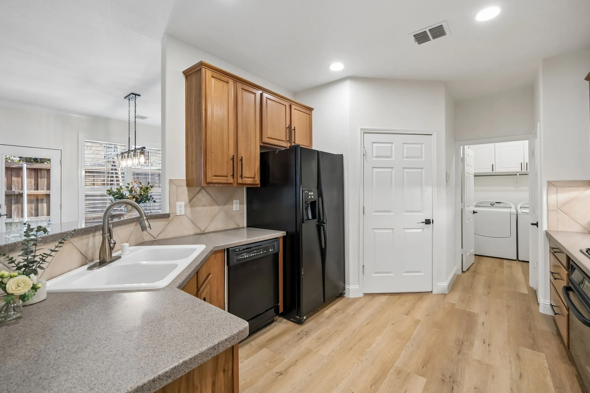 Kitchen featuring wood-finish cabinetry, solid surface countertops, and a dual-basin sink