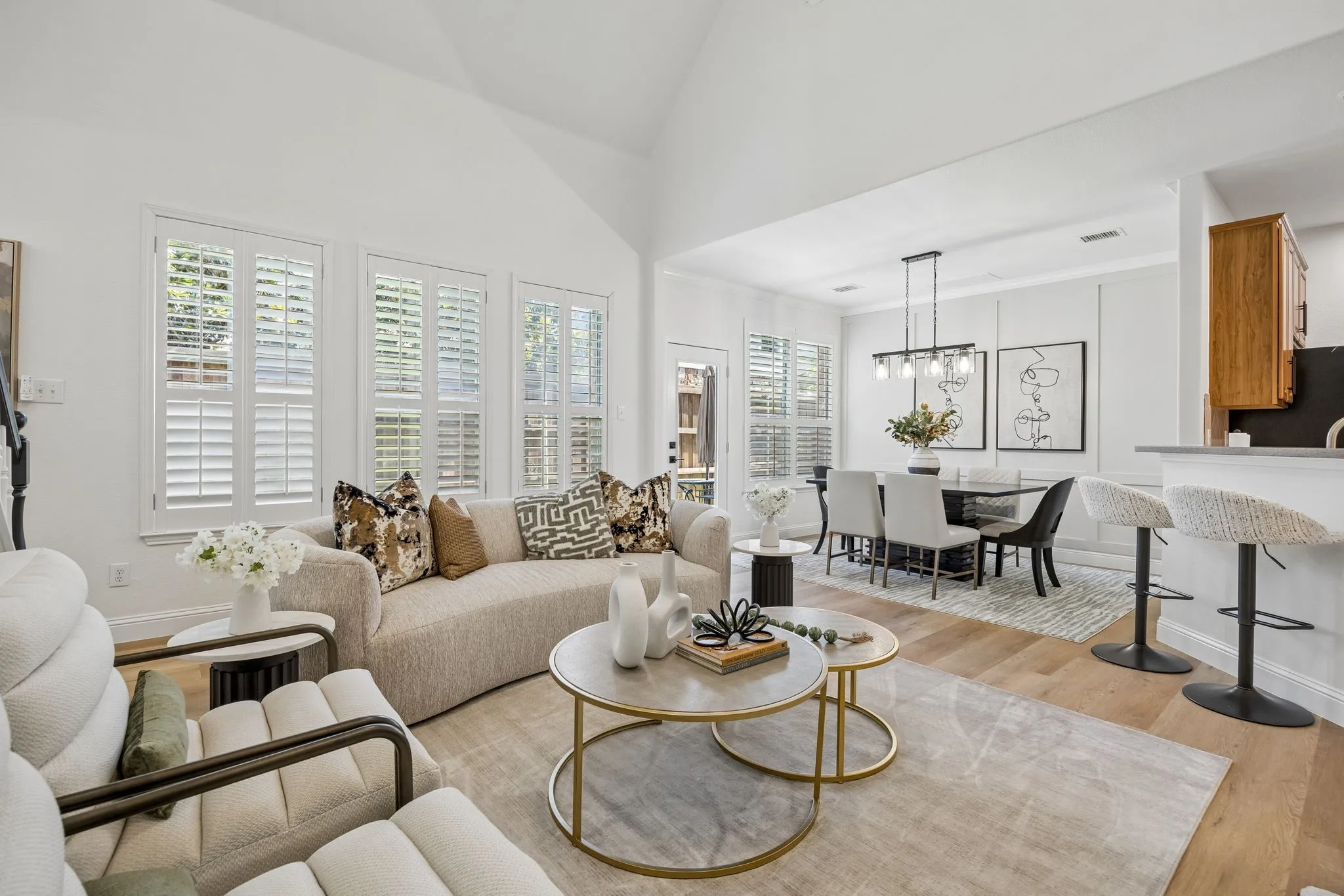 Living area featuring vaulted ceilings, wood-finish flooring, and multiple windows with plantation shutters