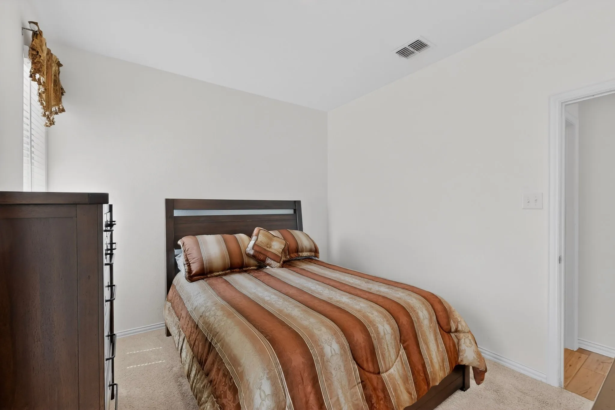 Carpeted room with a dark wood-finish headboard and light-toned walls