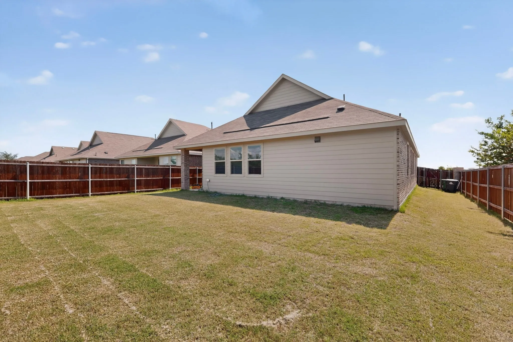 Expansive backyard featuring a manicured lawn and privacy fencing