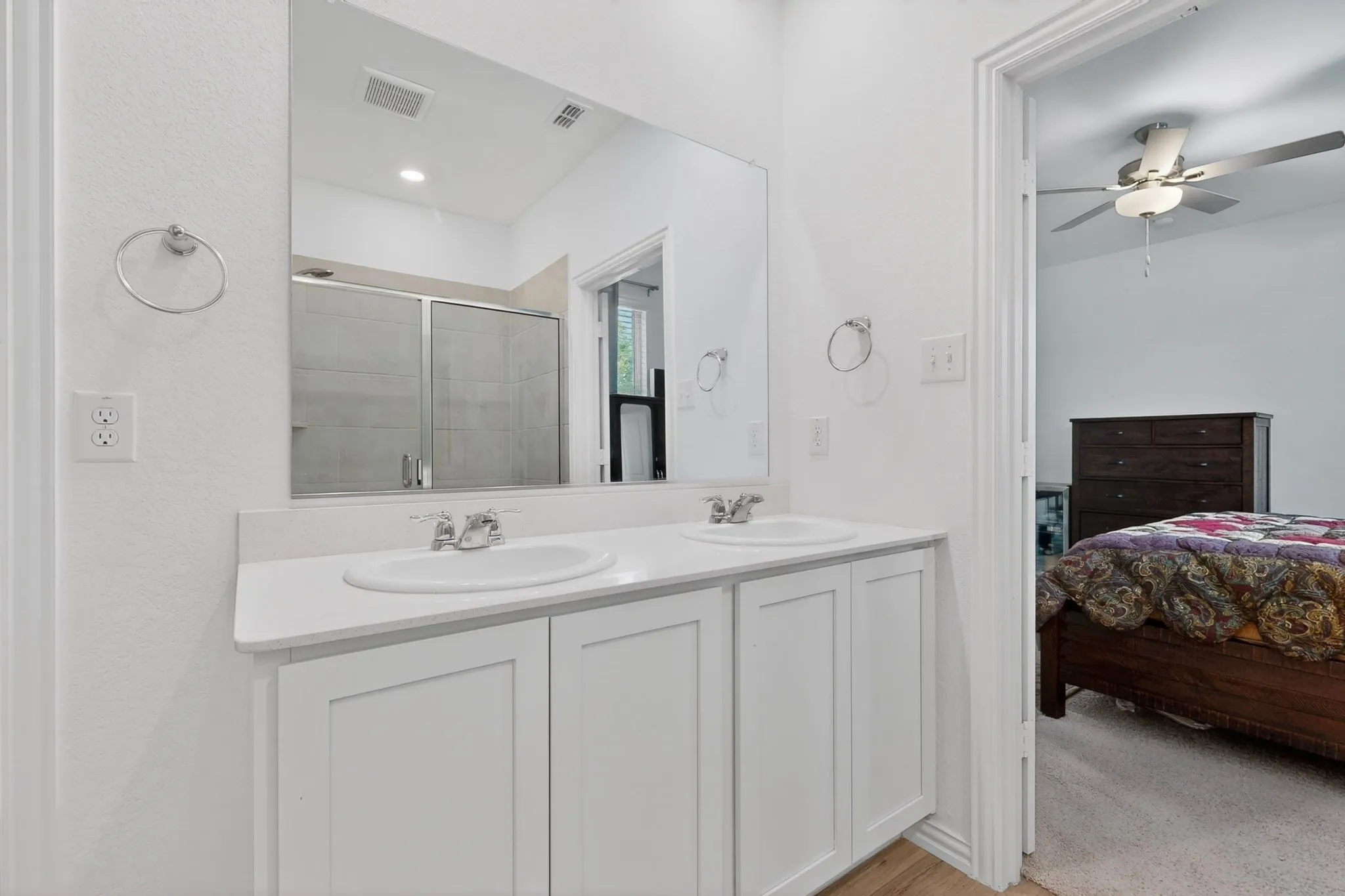 Bathroom featuring a double vanity with white cabinetry, integrated sinks, and chrome faucets