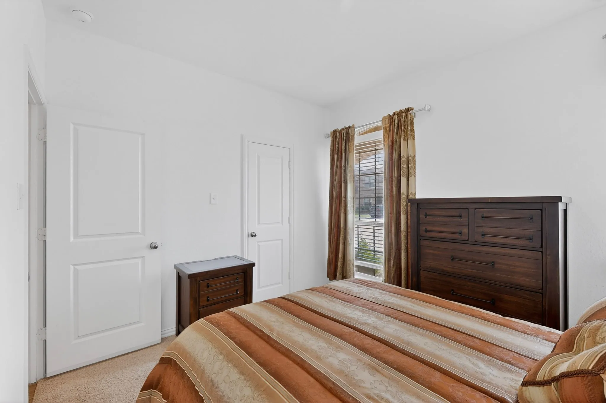 Bedroom featuring neutral wall paint, carpet flooring, a window with horizontal blinds, and two paneled interior doors