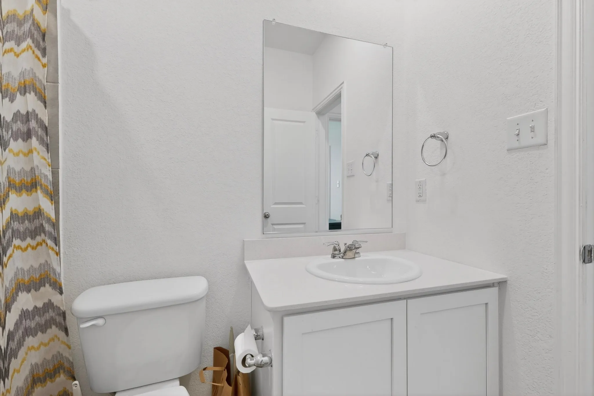 Bathroom vanity featuring an integrated sink, polished chrome faucet, and white cabinetry