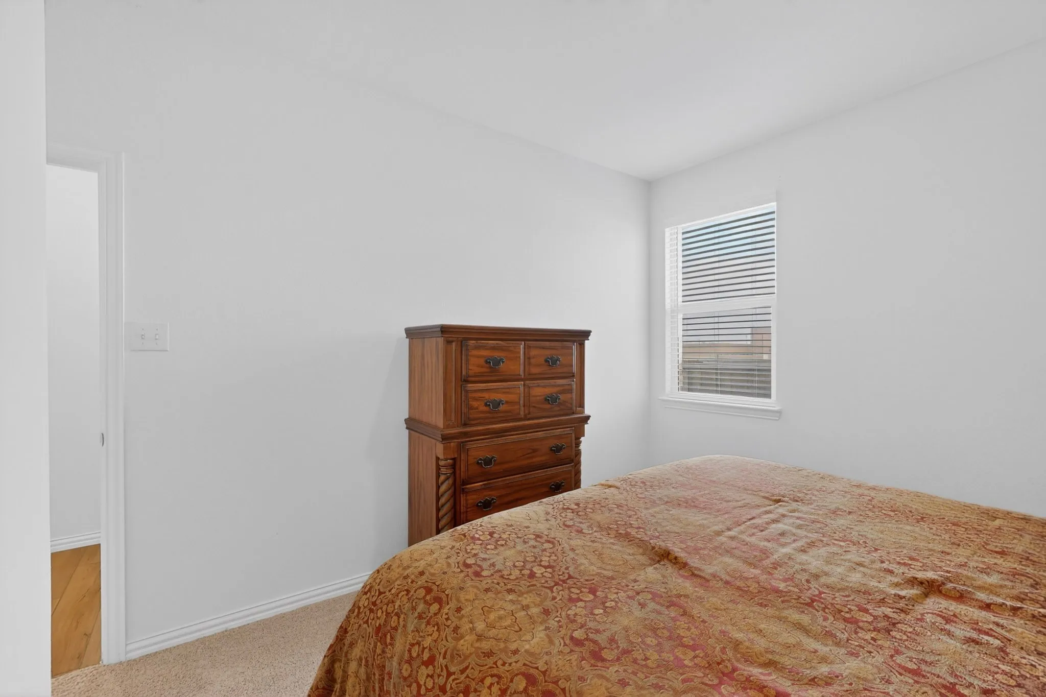 Carpeted room with a window featuring blinds
