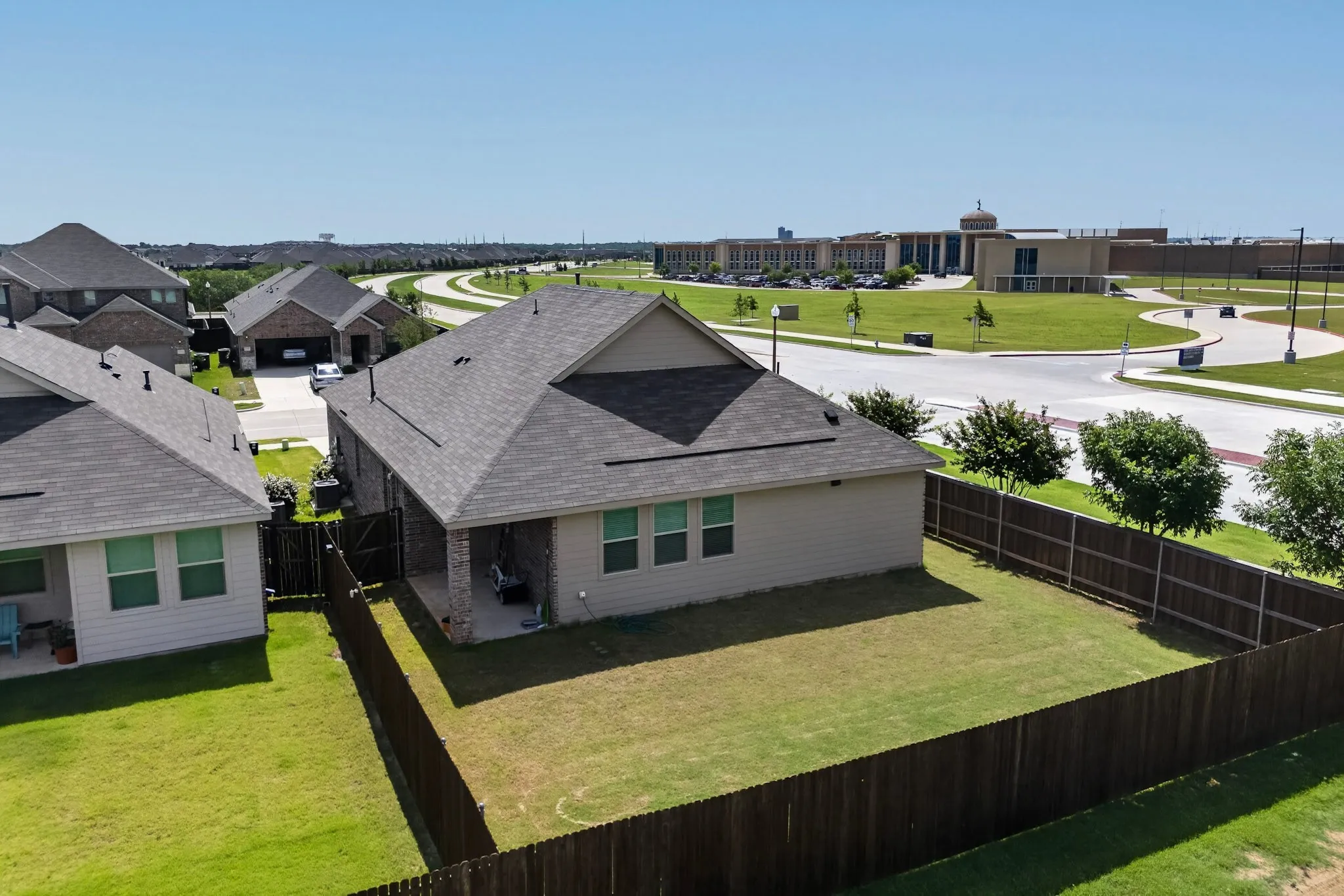 Fenced backyard with a covered patio and green lawn