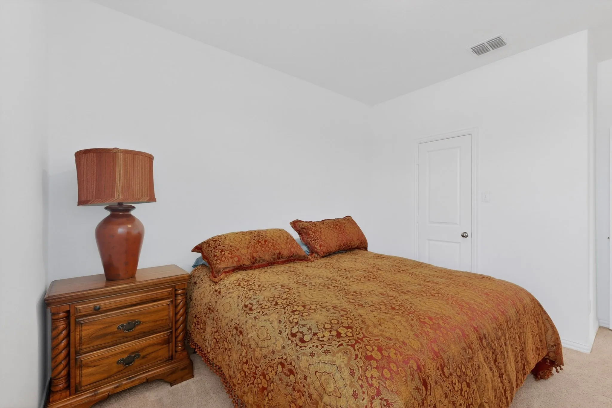 Carpeted room with a solid-core door and a white ceiling with recessed vents
