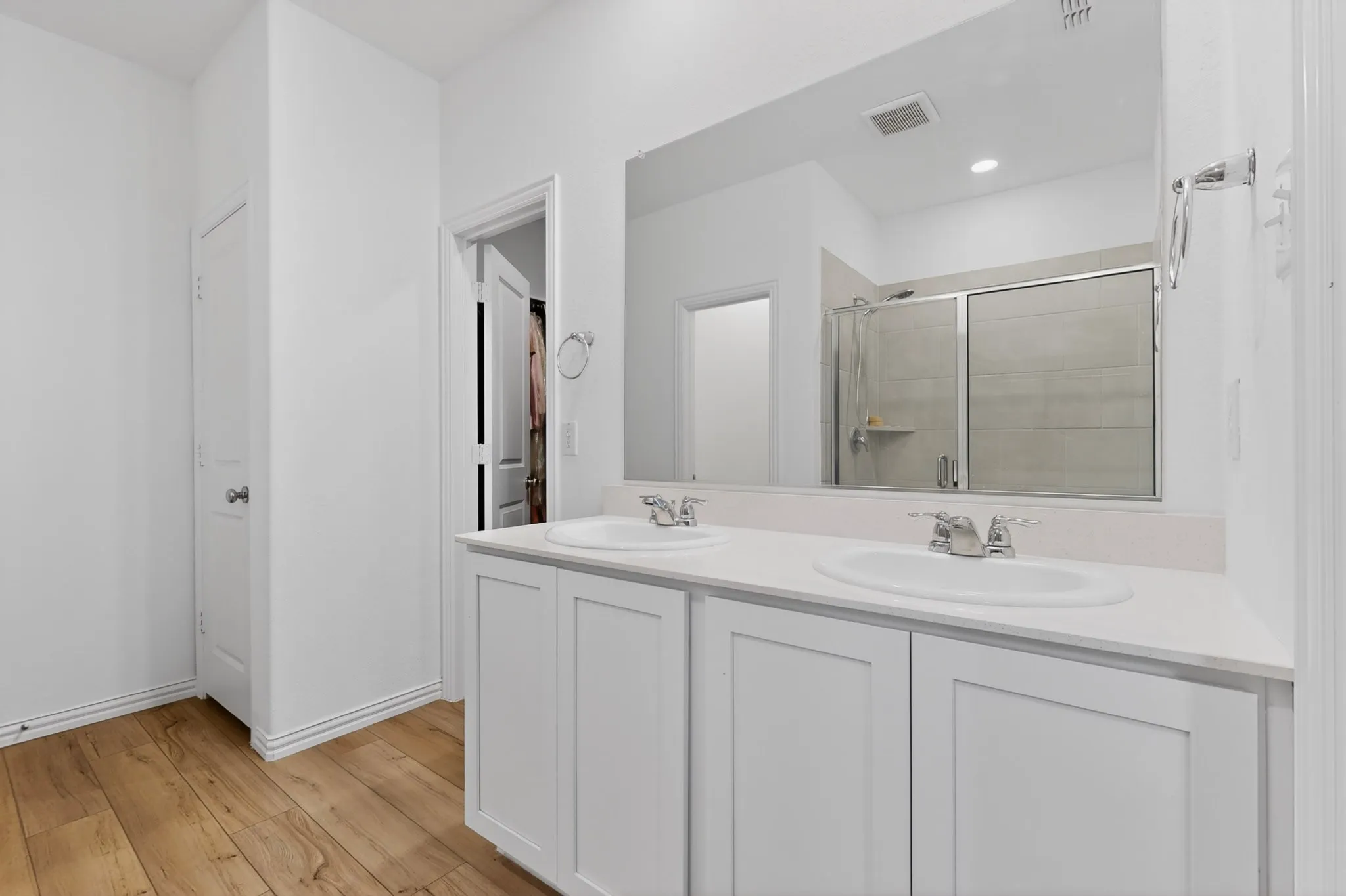 Bathroom featuring a double vanity with white cabinetry, light-colored countertops, and dual undermount sinks
