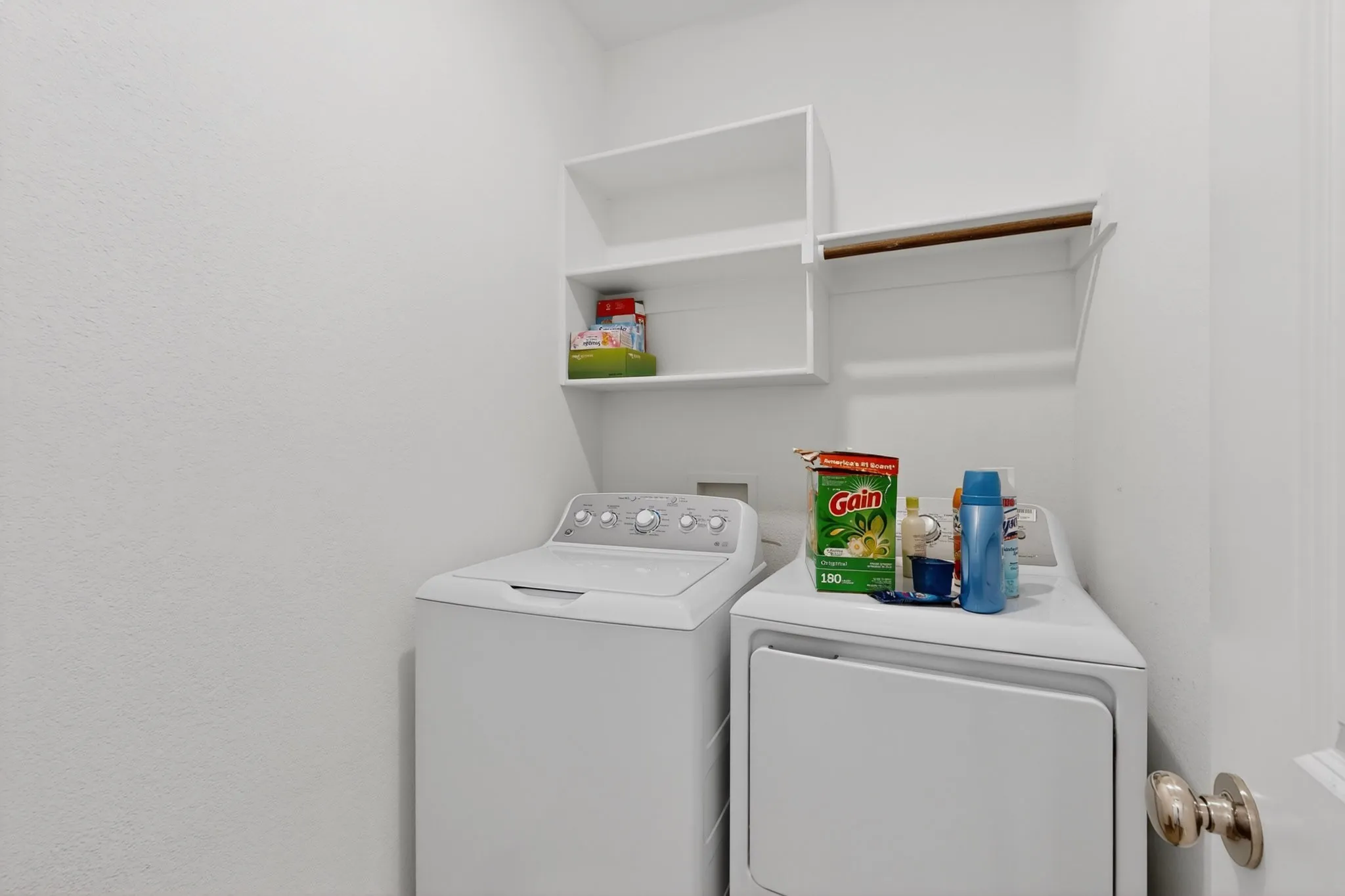 Dedicated utility space featuring open shelving and a clothing rod