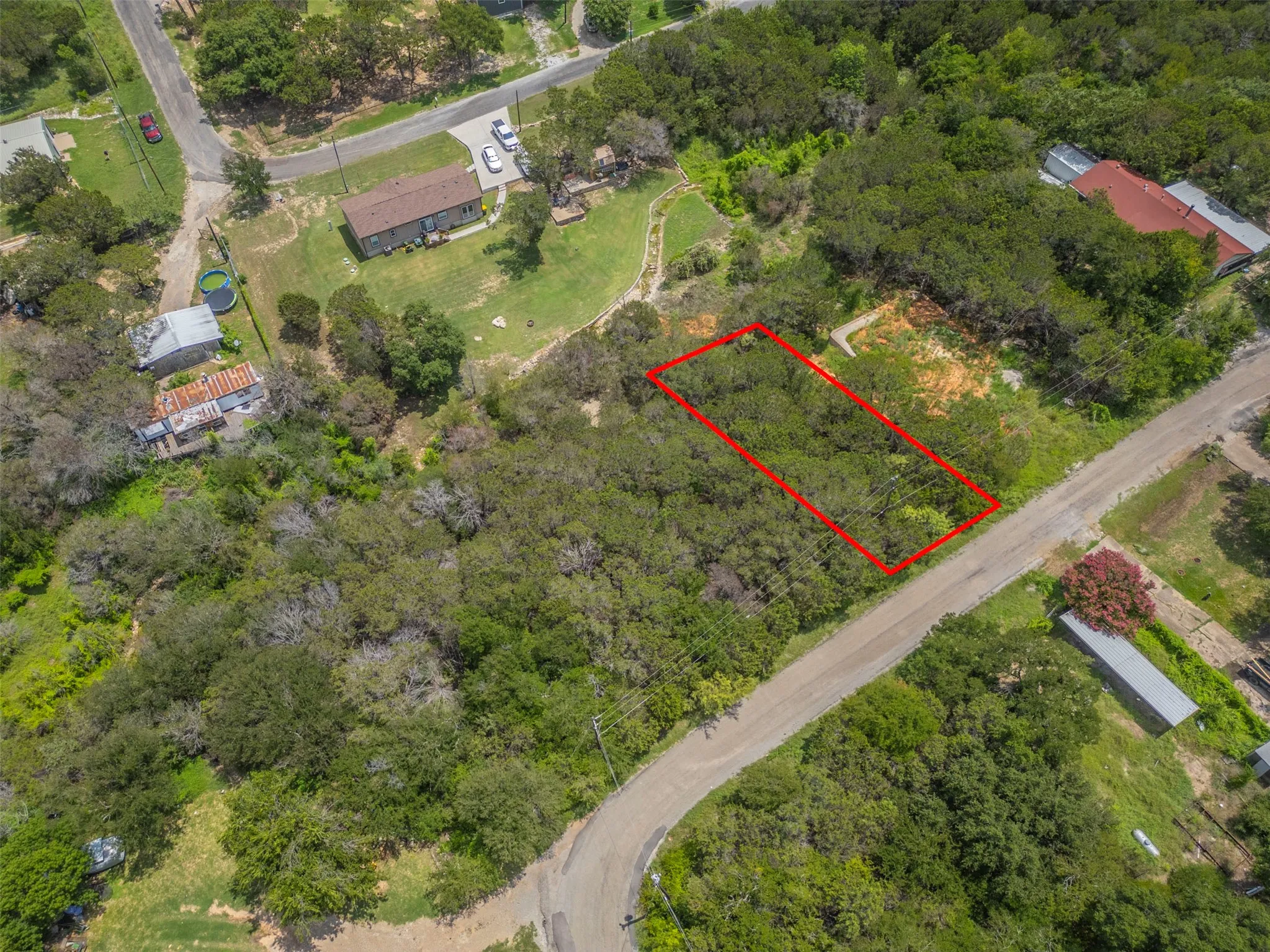 Wooded residential lot featuring a rectangular property boundary and direct road frontage