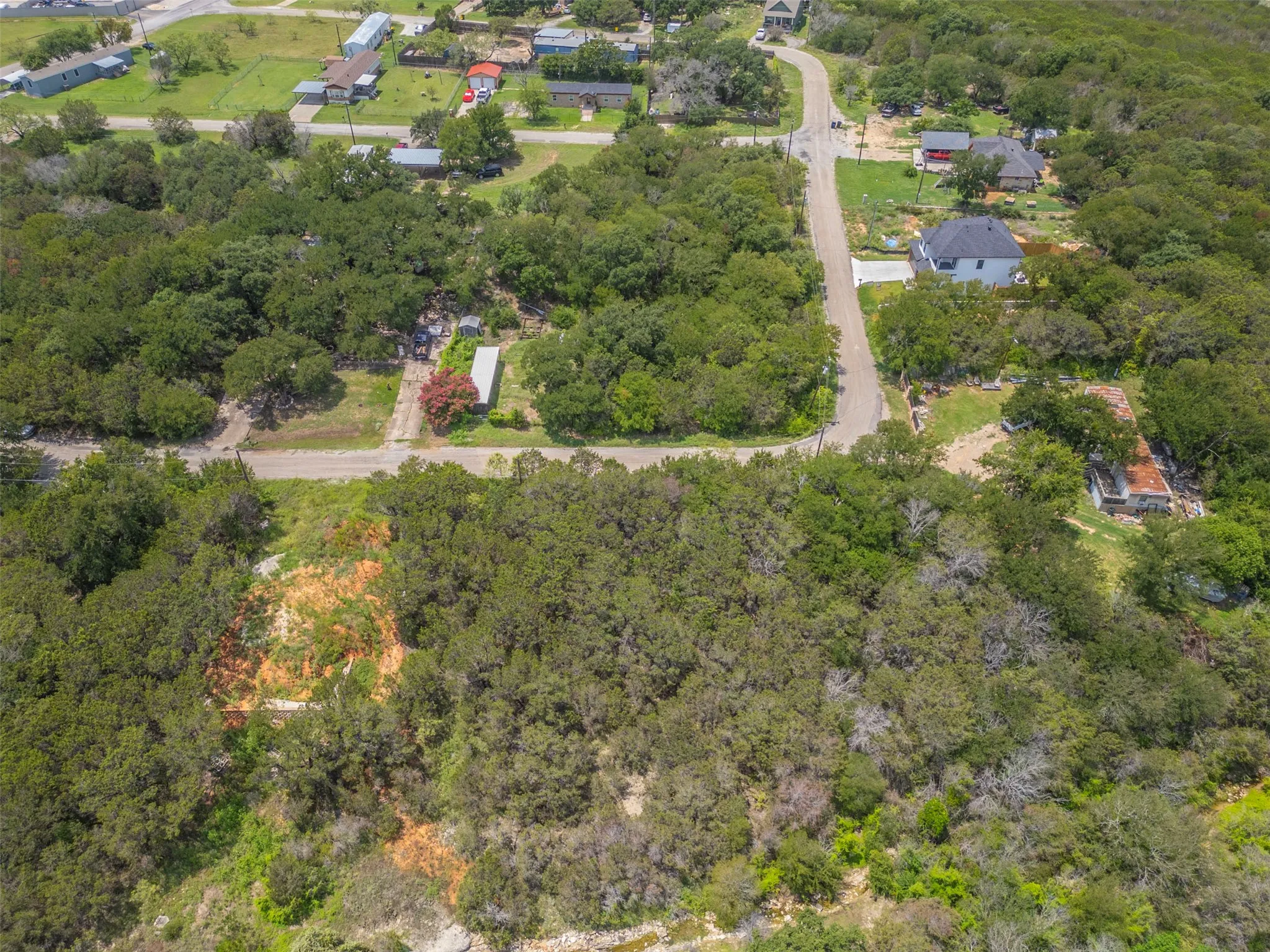 Expansive wooded land featuring a partially cleared area, mature trees, and unpaved roads