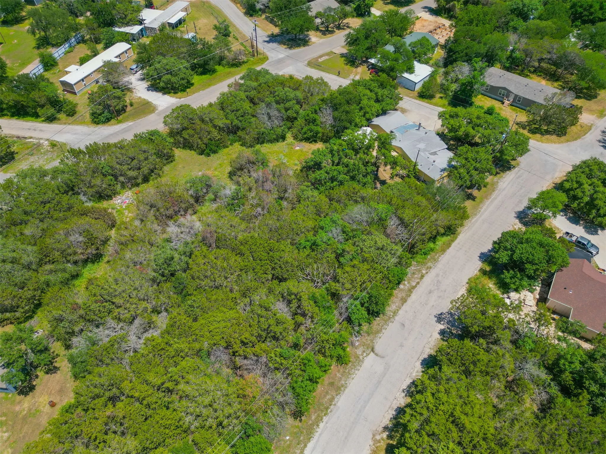 Expansive land parcel featuring dense mature trees and clearings, bordered by paved roads