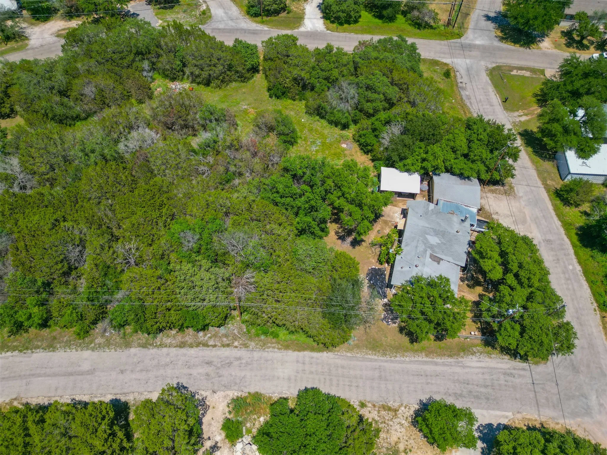 Expansive parcel featuring a main residence with a gray roof, surrounded by mature trees