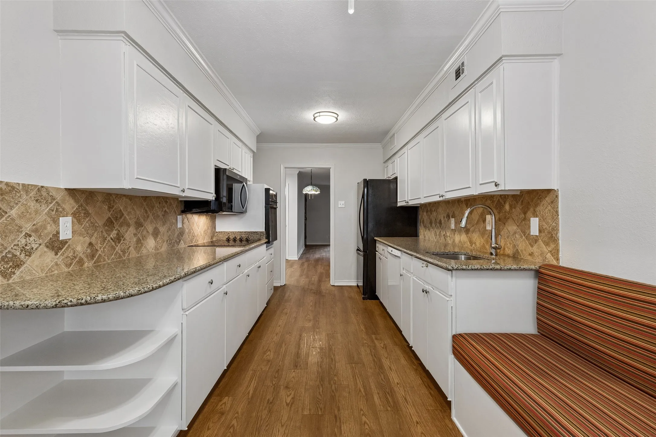 Spacious kitchen offers painted cabinets, granite counters, and a built-in banquette with storage below for casual dining.