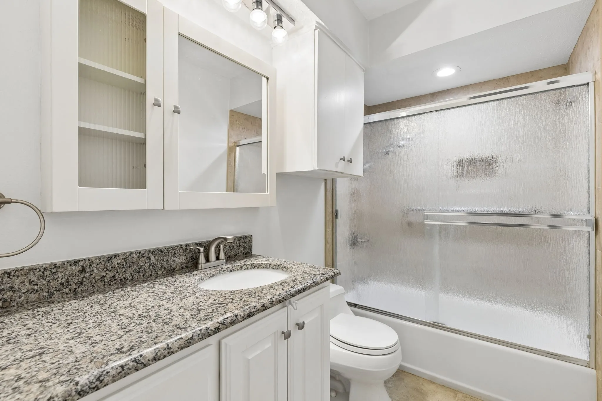 Guest bathroom features granite countertops, a shower tub combination, and painted cabinetry