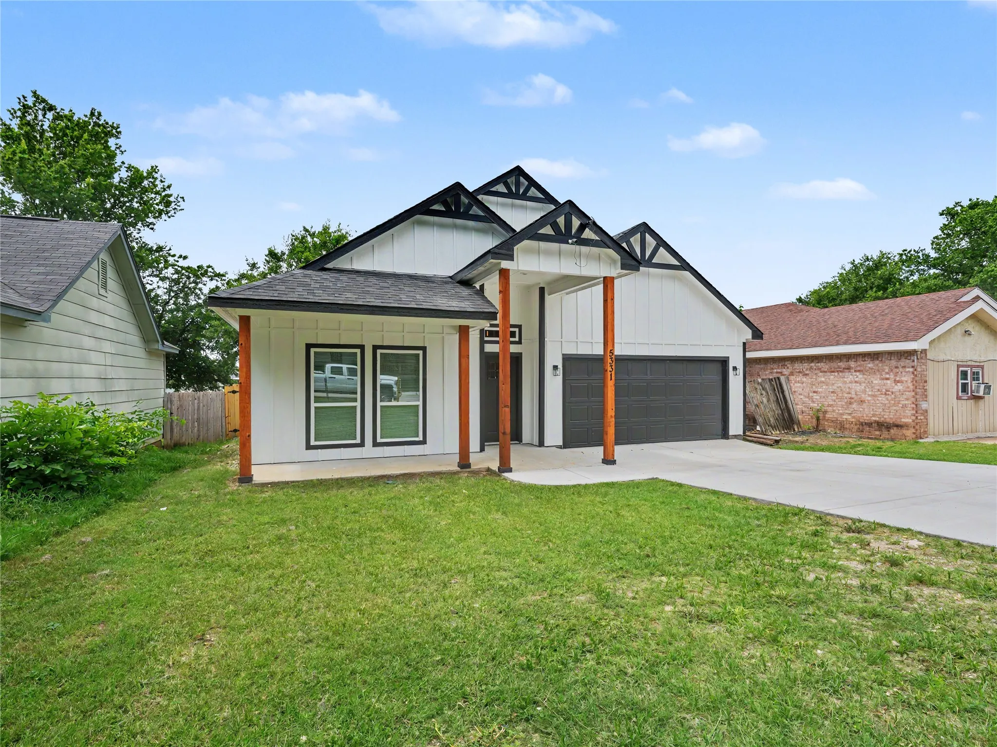 Modern farmhouse exterior featuring white board-and-batten siding, a dark gray garage door, and black-trimmed gables