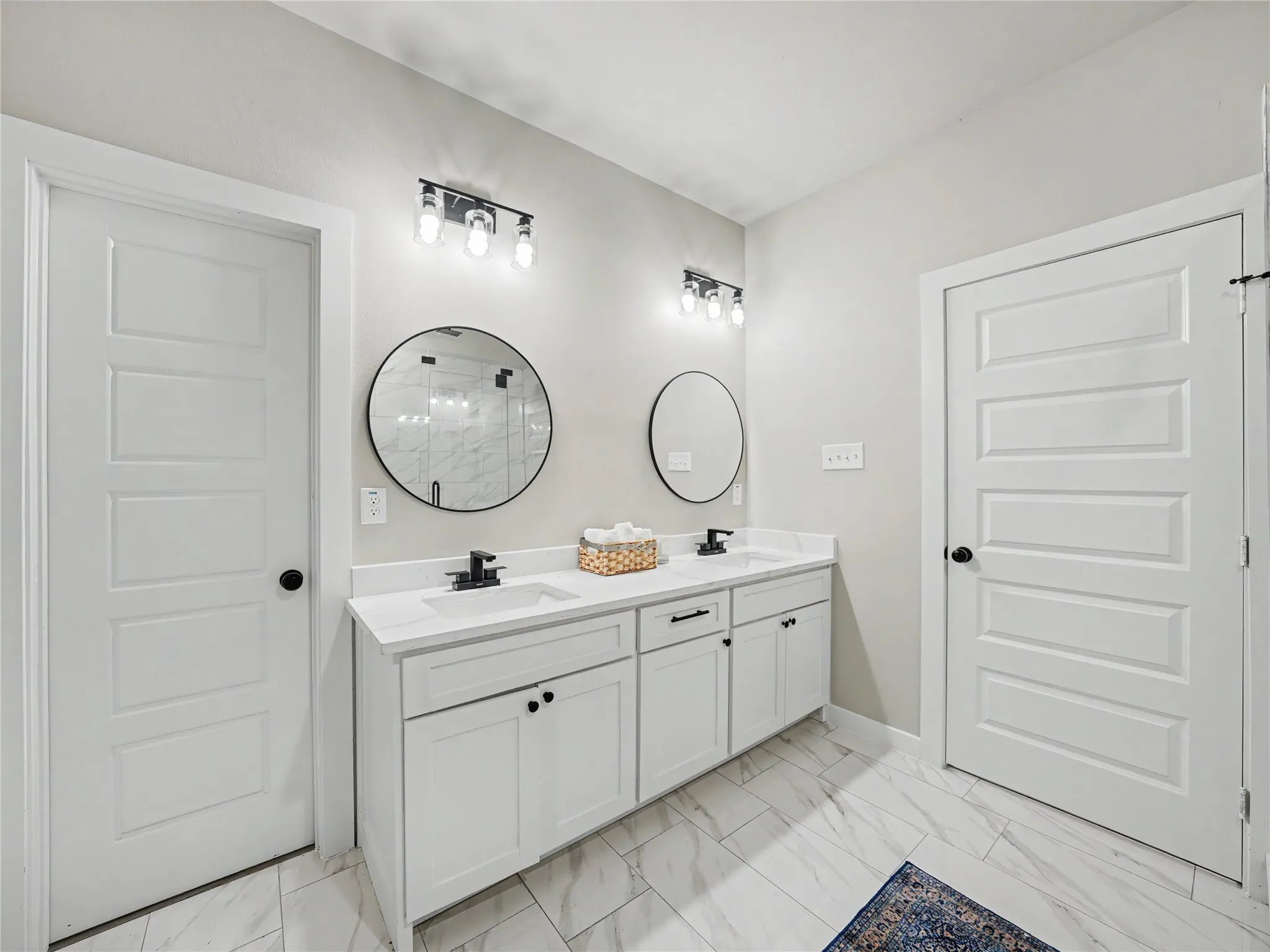 Dual vanity featuring white shaker cabinetry, white countertops, undermount sinks, and matte black hardware