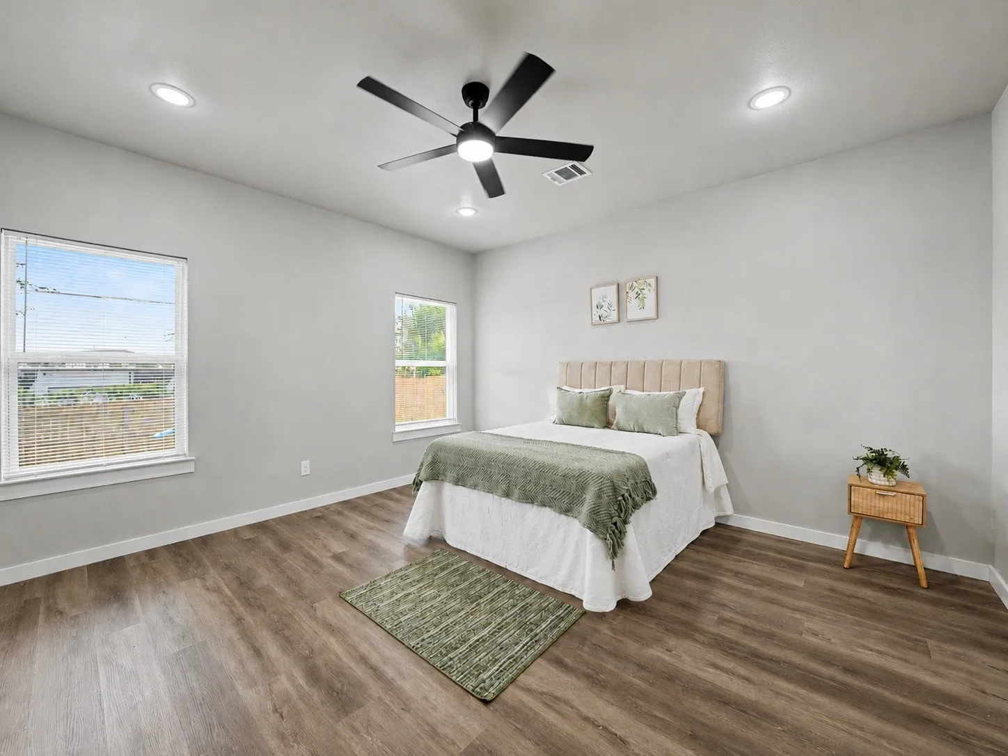 Spacious room featuring wood-finish flooring, light grey walls, and a contemporary ceiling fan with integrated lighting