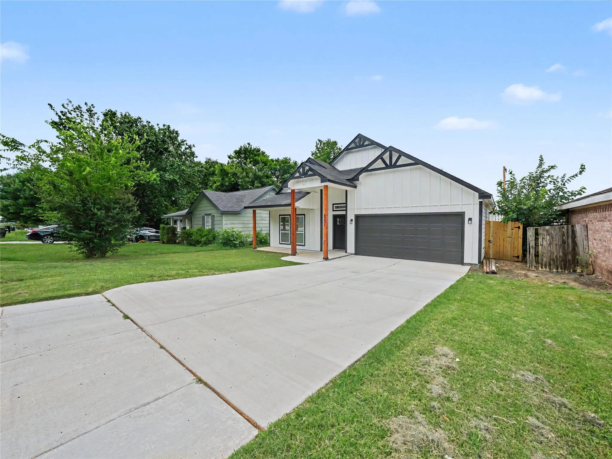 Modern farmhouse-style exterior with white board and batten siding, dark trim accents, and a dark garage door