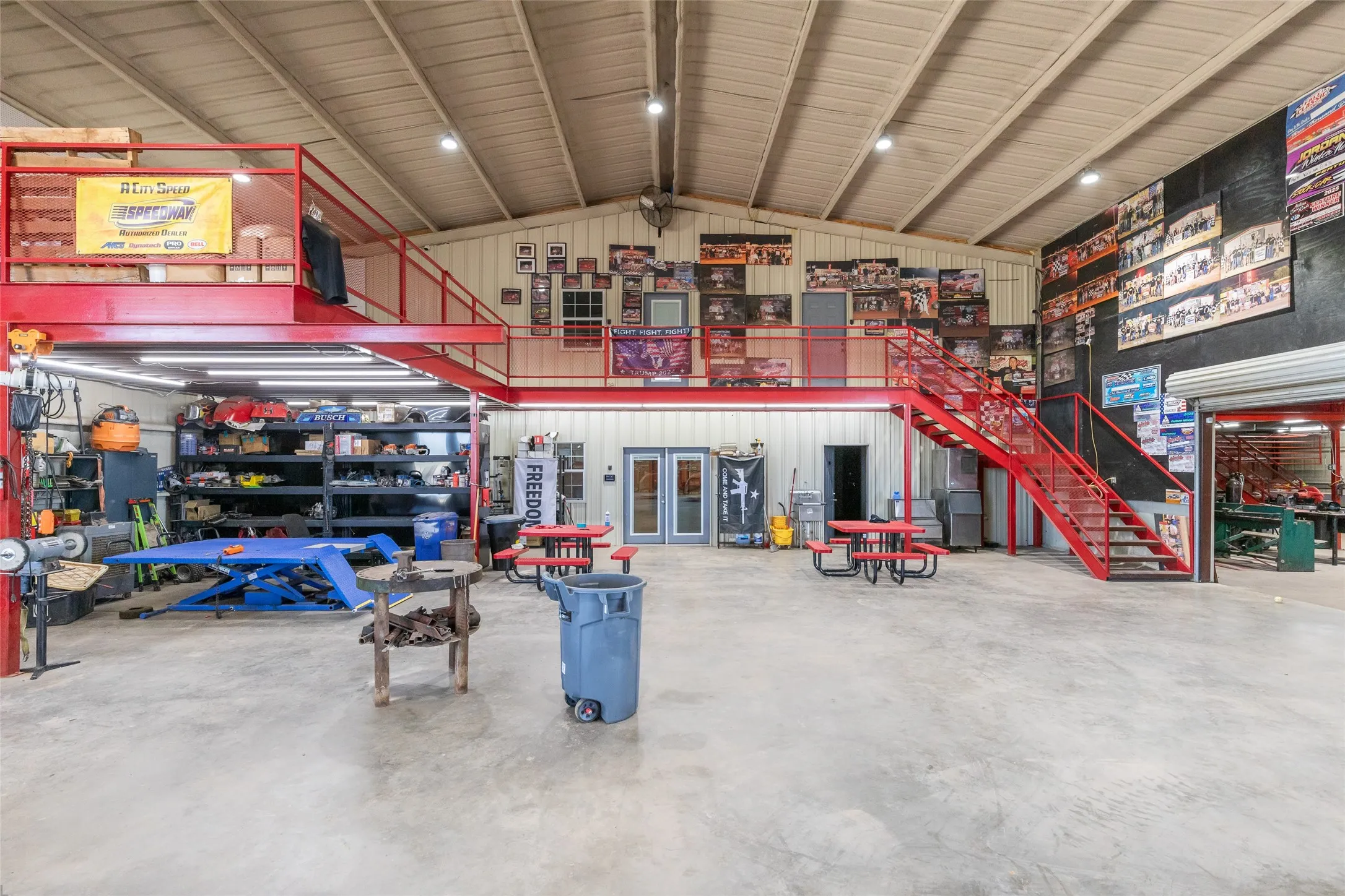 Spacious interior featuring a concrete floor, high vaulted ceiling, and an expansive red metal mezzanine