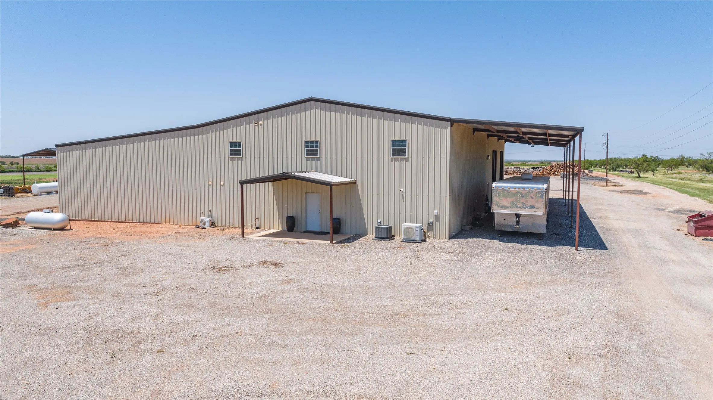 Expansive metal building featuring a pitched roofline, multiple windows, covered entry, and an additional covered outdoor area