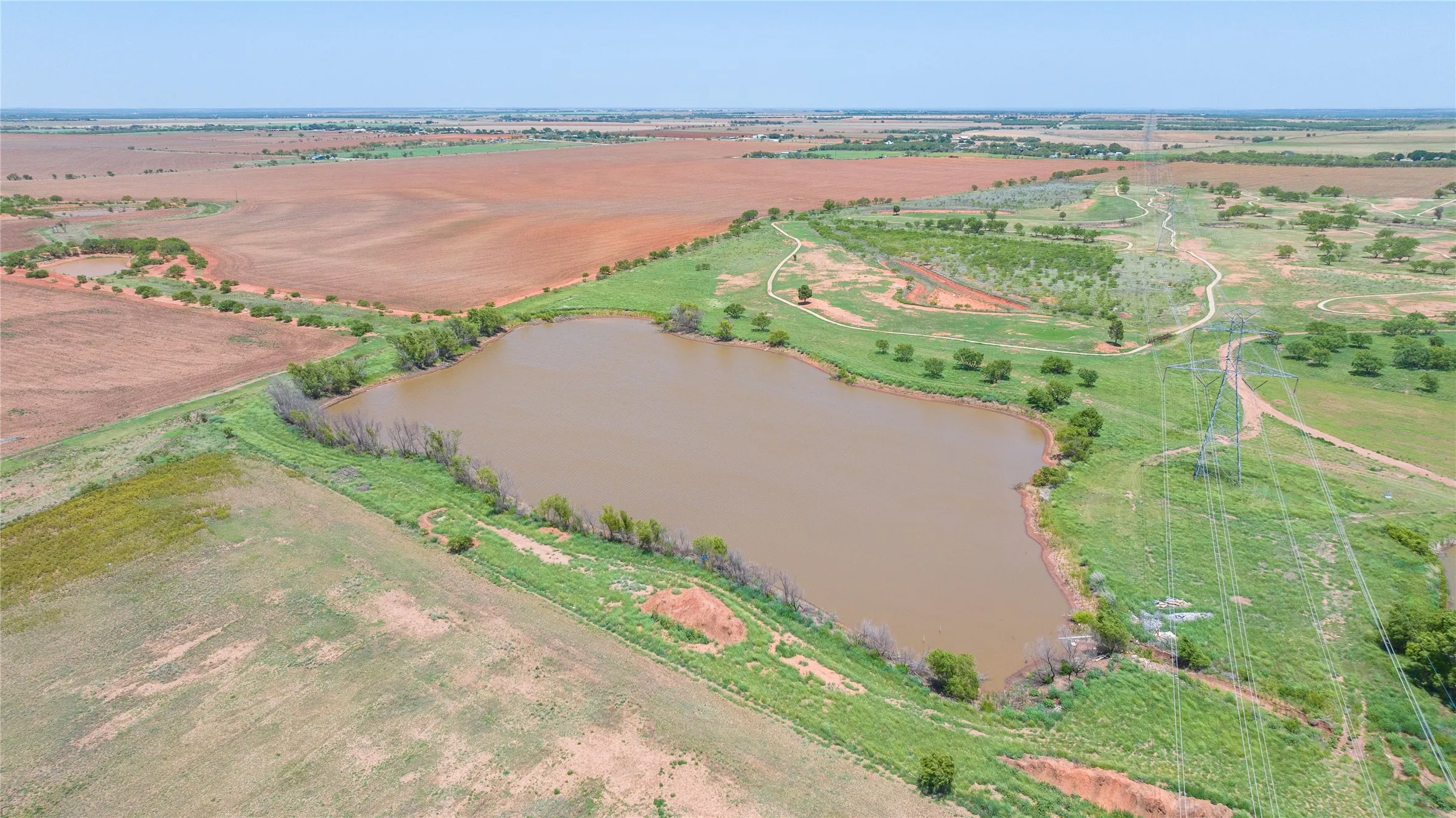 Aerial perspective showcasing a large body of water bordered by green grass and scattered trees