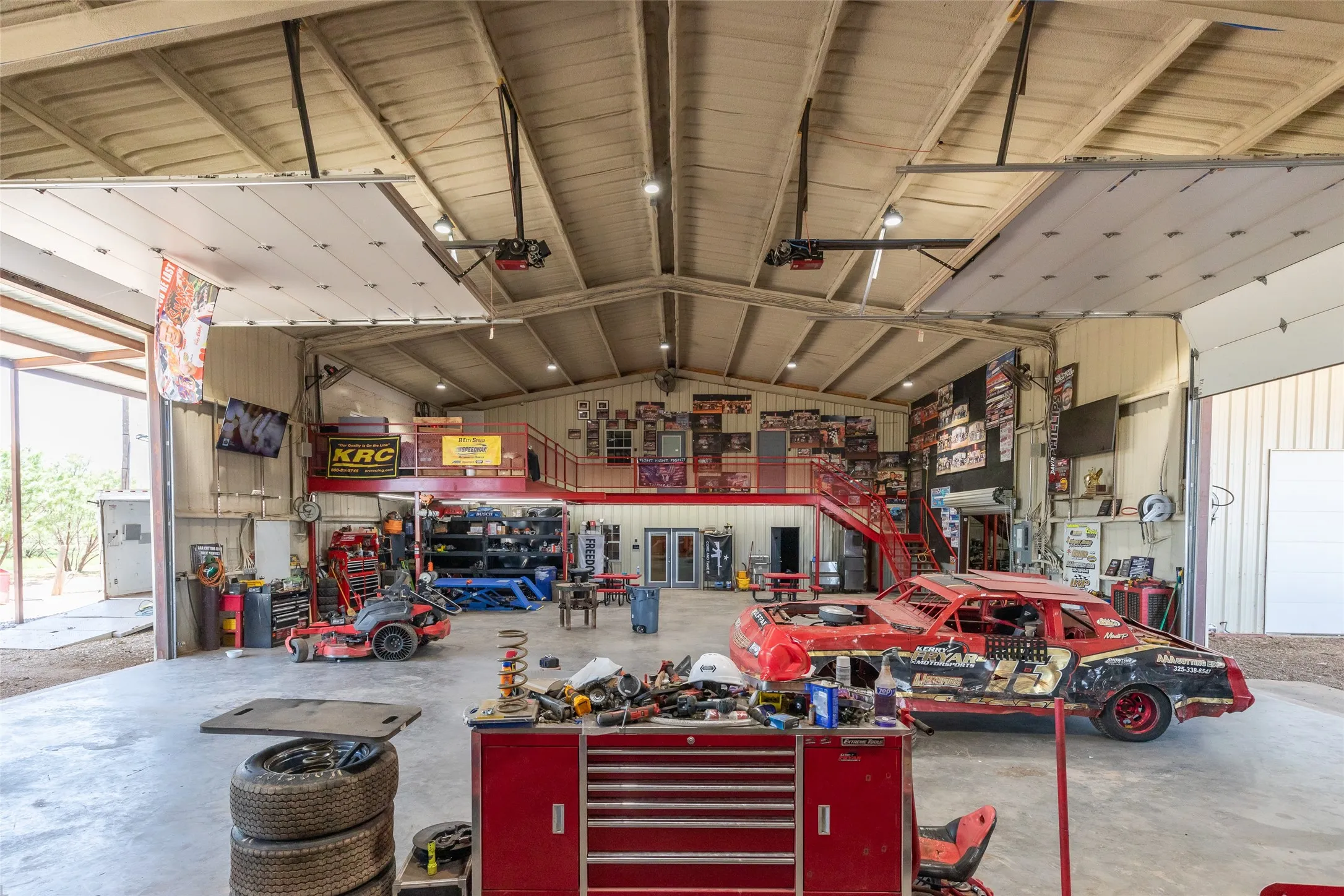 Spacious industrial-style workshop featuring a high vaulted ceiling with exposed beams and recessed lighting