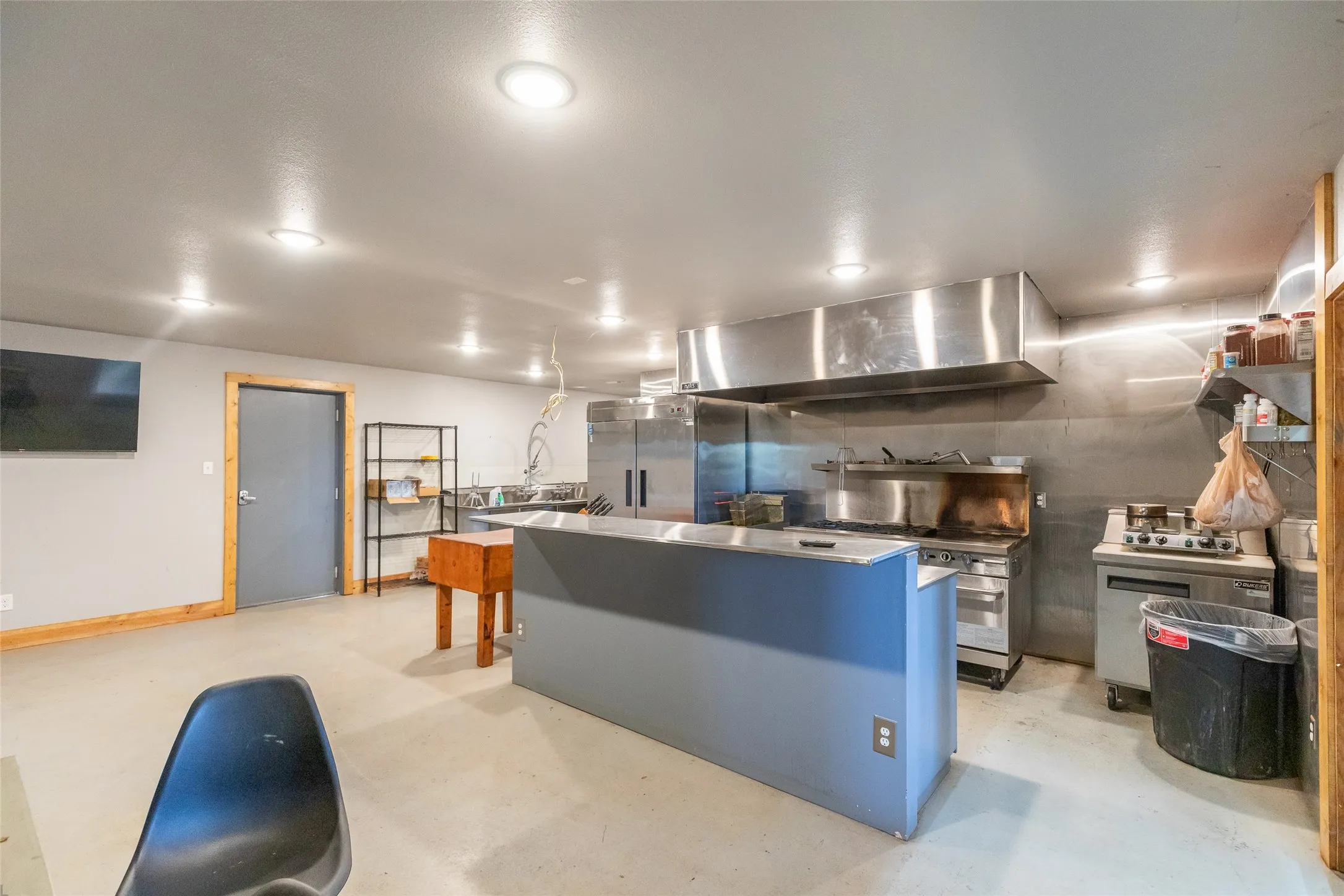 Commercial-grade kitchen featuring stainless steel appliances, expansive ventilation hood, and dedicated prep island
