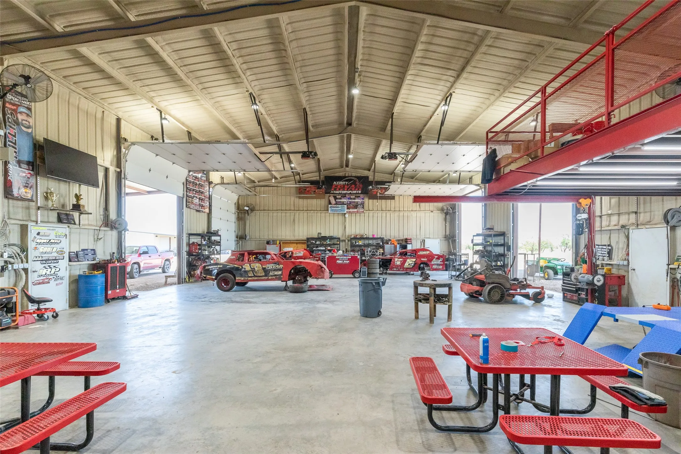 Spacious industrial-style interior featuring high ceilings, concrete flooring, and multiple overhead doors
