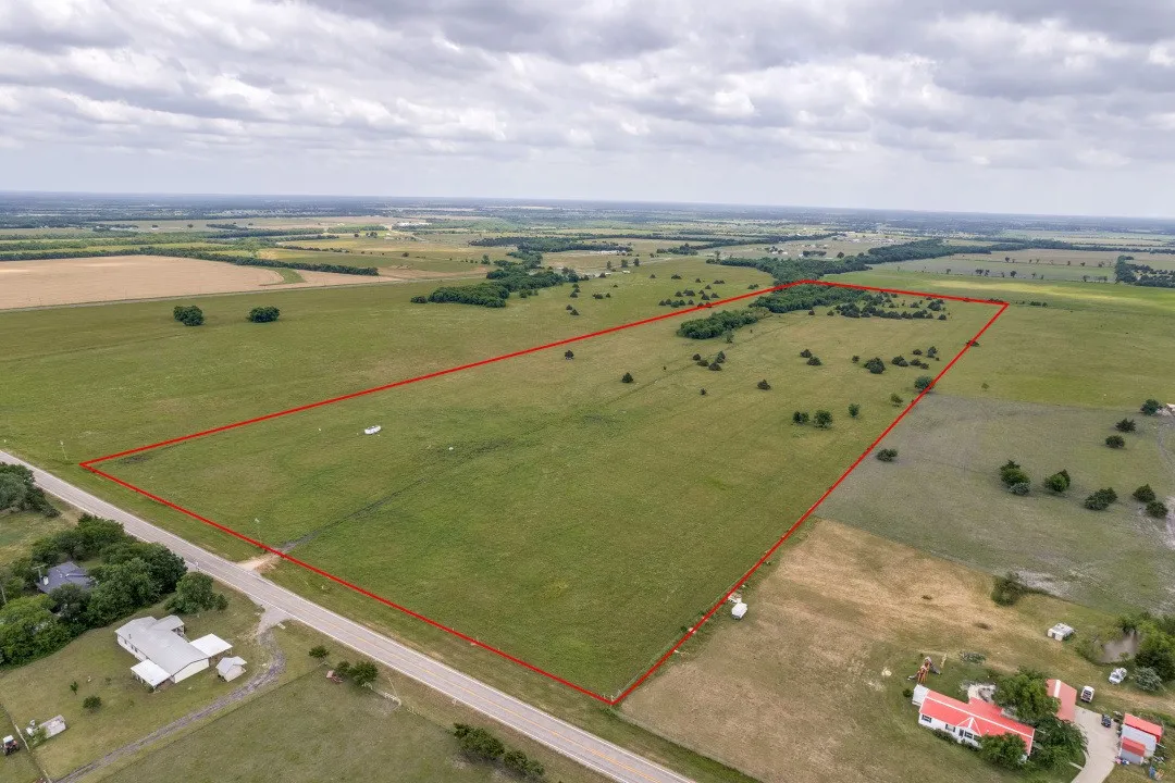 Expansive agricultural parcel featuring open fields and scattered mature trees