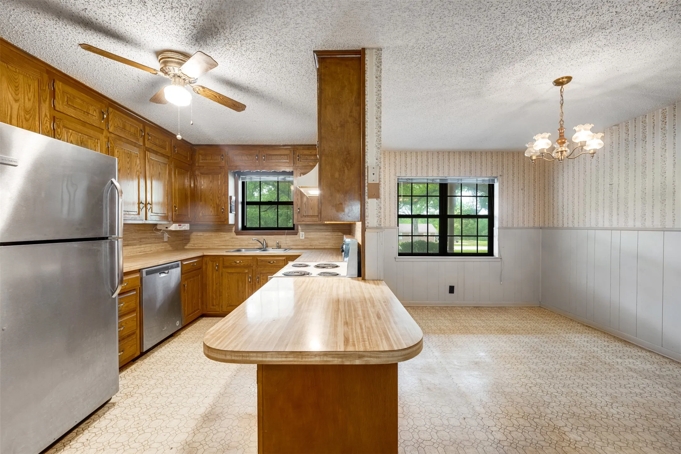 Kitchen featuring ample wood cabinetry, stainless steel refrigerator and dishwasher, and a built-in electric stovetop