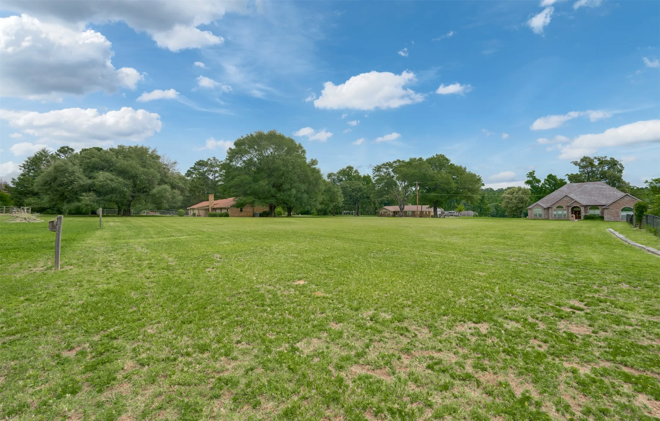 Expansive grassy area with lush trees bordering the property