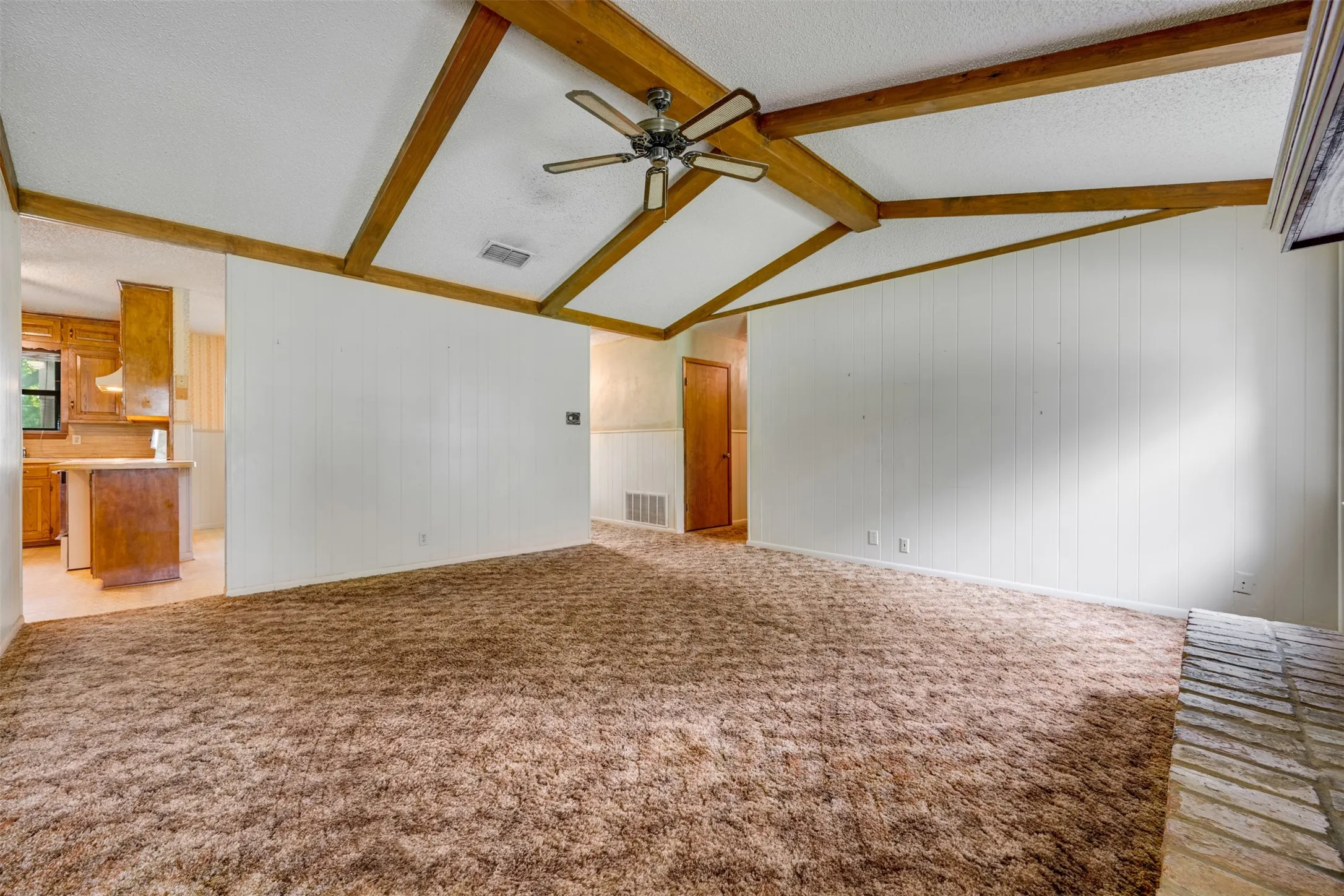 Vaulted ceiling with exposed wood beams and a ceiling fan