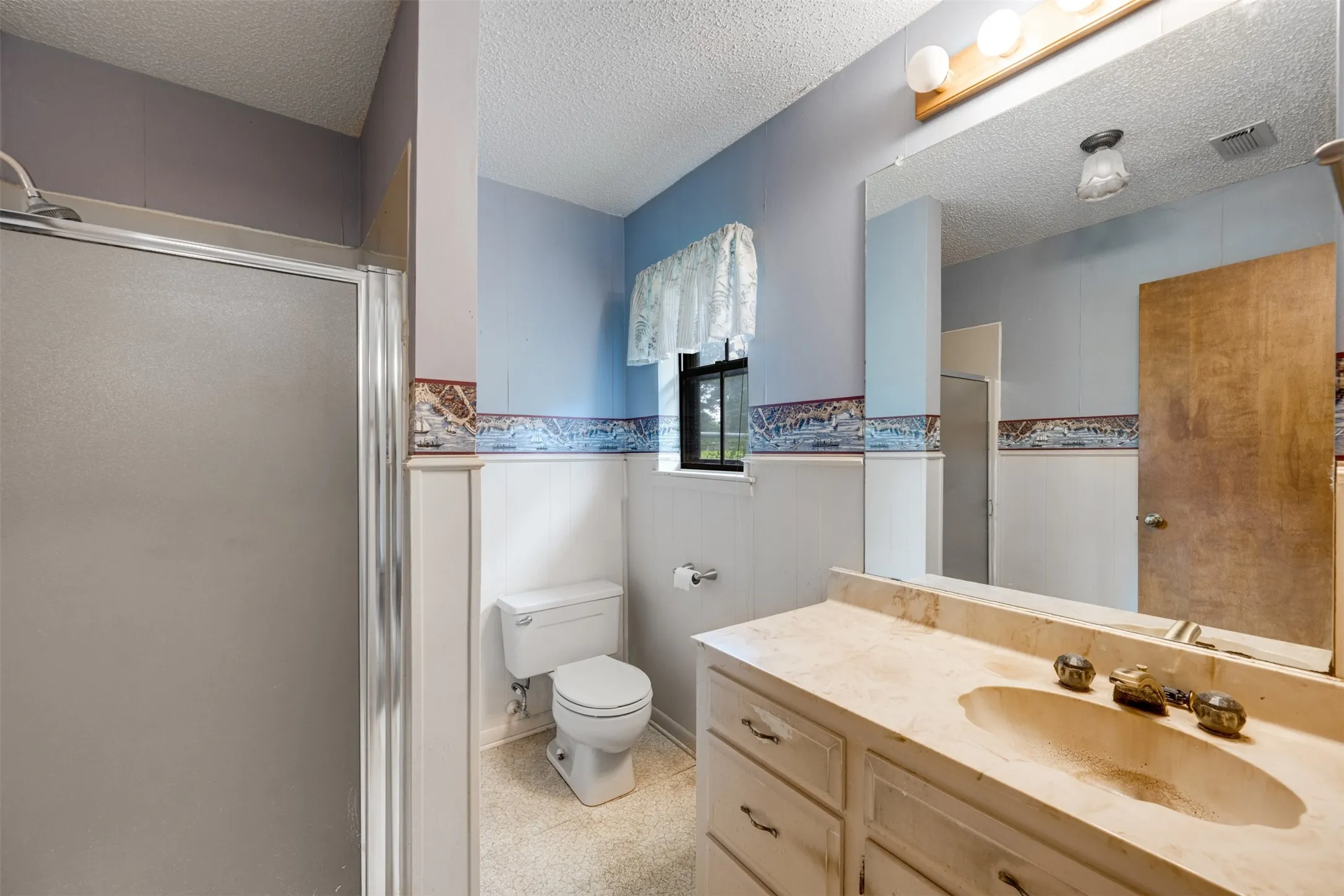 Bathroom featuring a shower with a frosted glass enclosure, a vanity with an integrated sink and light-colored countertop, and a built-in toilet