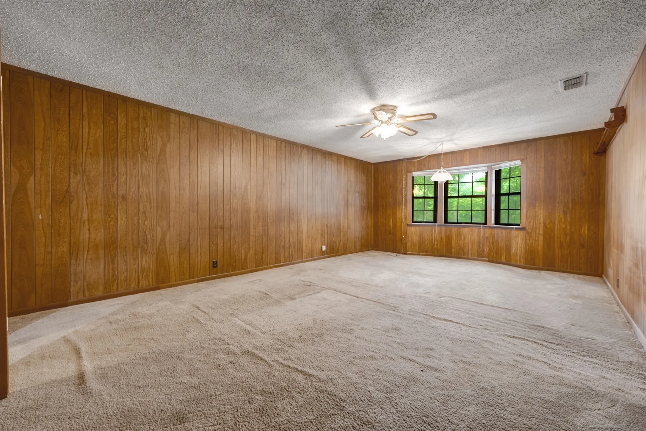 Spacious interior with full wood paneling and a textured ceiling