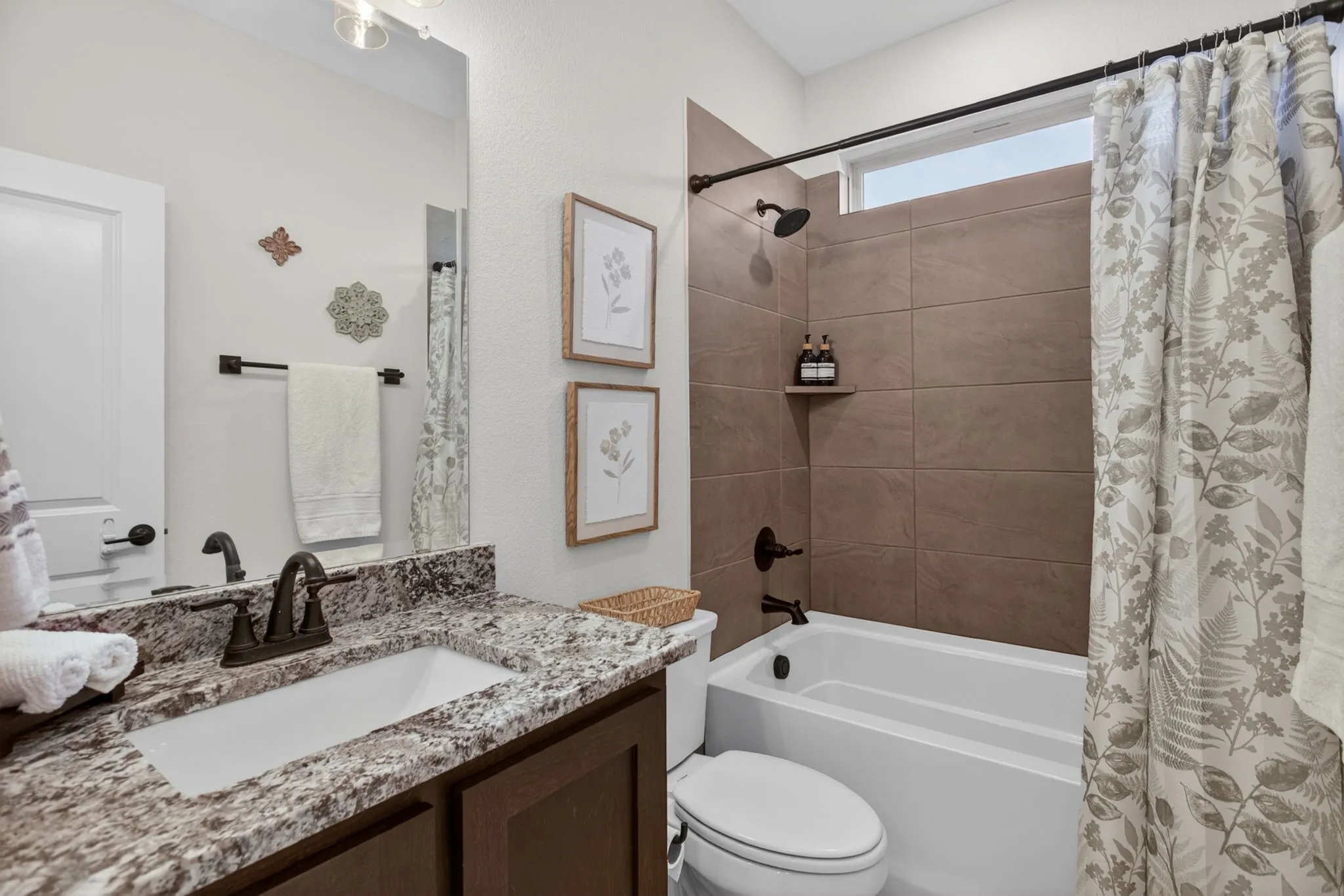 Downstairs guest bathroom with tiled tub-shower combo, nice fixtures and pretty countertops. Bloomfield always has nice details!