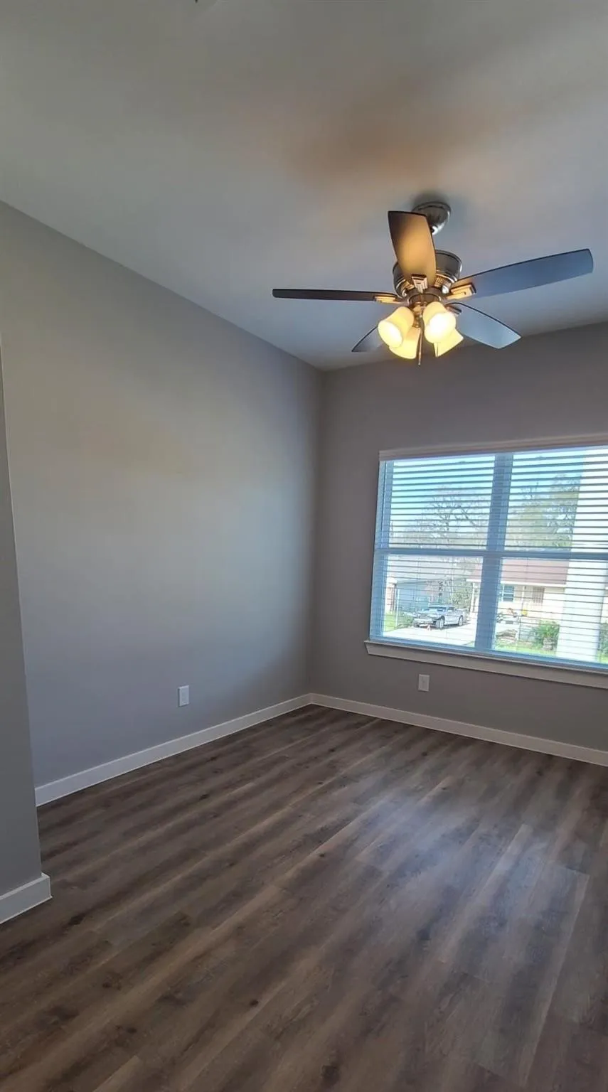 Bedroom 3 - Spacious room featuring vinyl flooring, light gray walls, and a large window with blinds