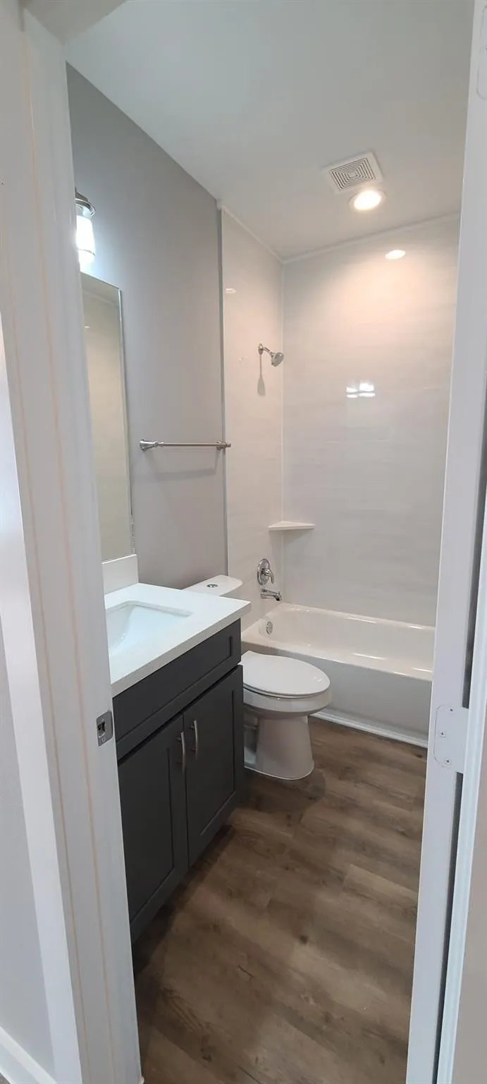 Bathroom 2 - Contemporary bathroom featuring a modern vanity with a white countertop and dark gray cabinetry, a white toilet, and a bathtub with white subway tile surround