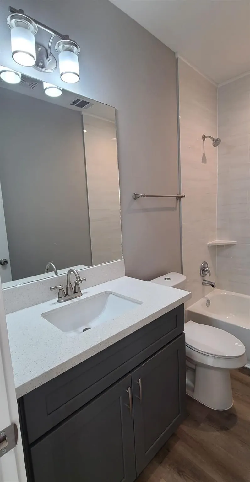 Bathroom 1 -  featuring a dark gray vanity with a light countertop, an integrated sink, and a brushed nickel faucet
