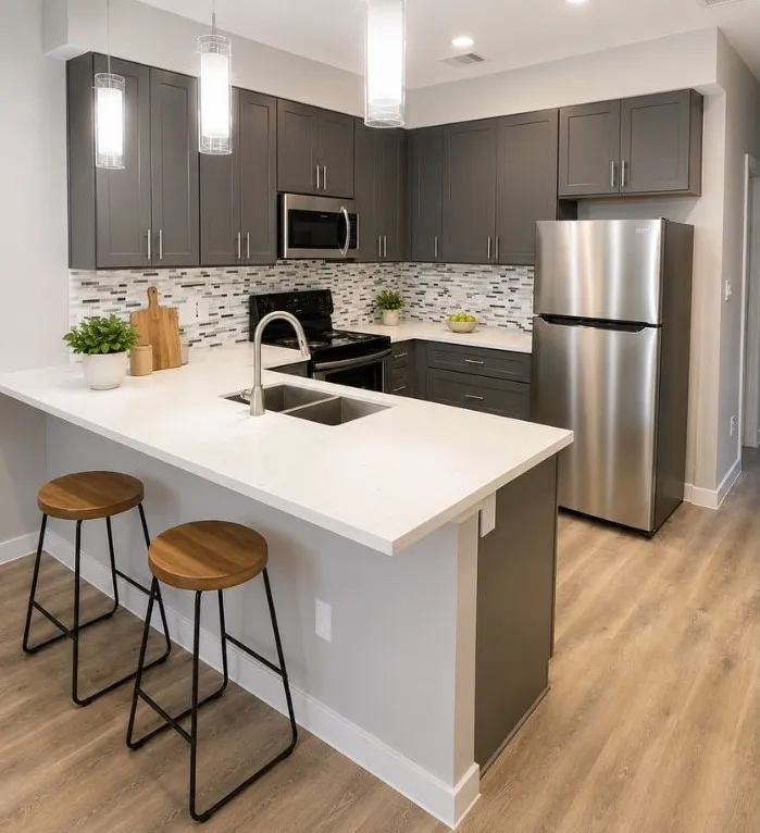 Virtually Staged - Modern kitchen featuring dark gray cabinetry, stainless steel appliances, white countertops, and a mosaic tile backsplash