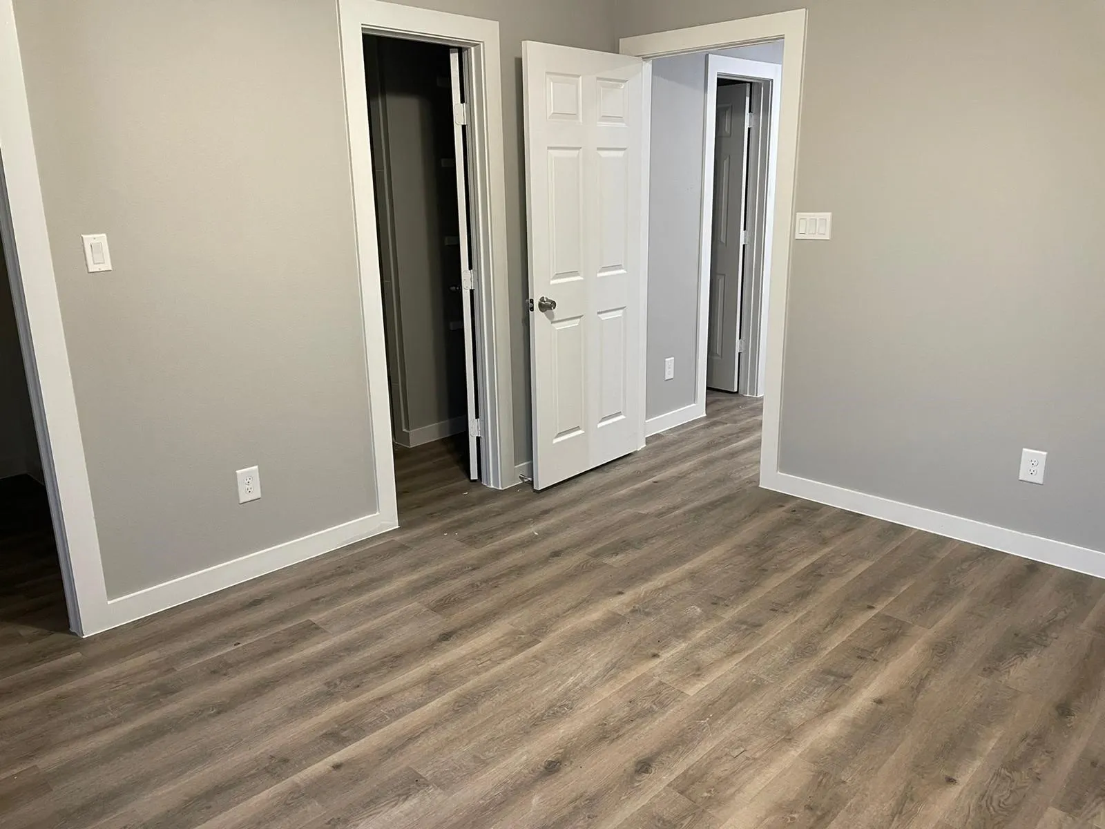 Neutral-toned interior featuring vinyl flooring, light gray walls, white trim, and a white paneled door