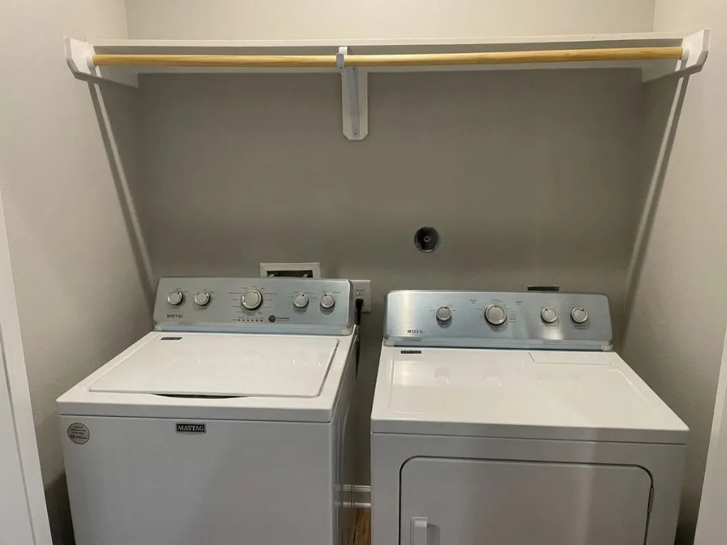 Dedicated laundry area featuring a white washing machine, white dryer, and an overhead drying rod
