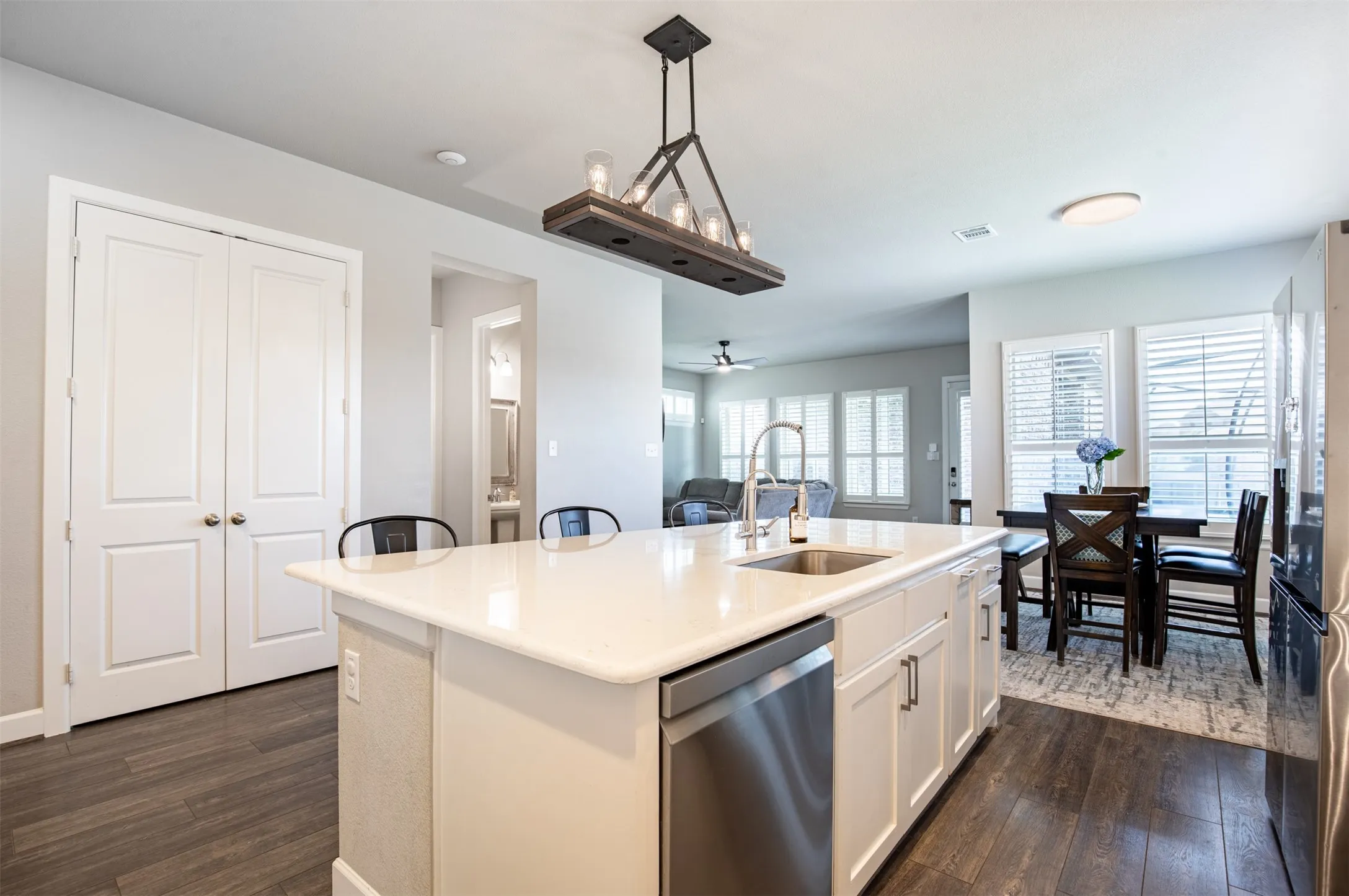 Large kitchen island with decorative lighting and extra seating.  Double doors lead to pantry.