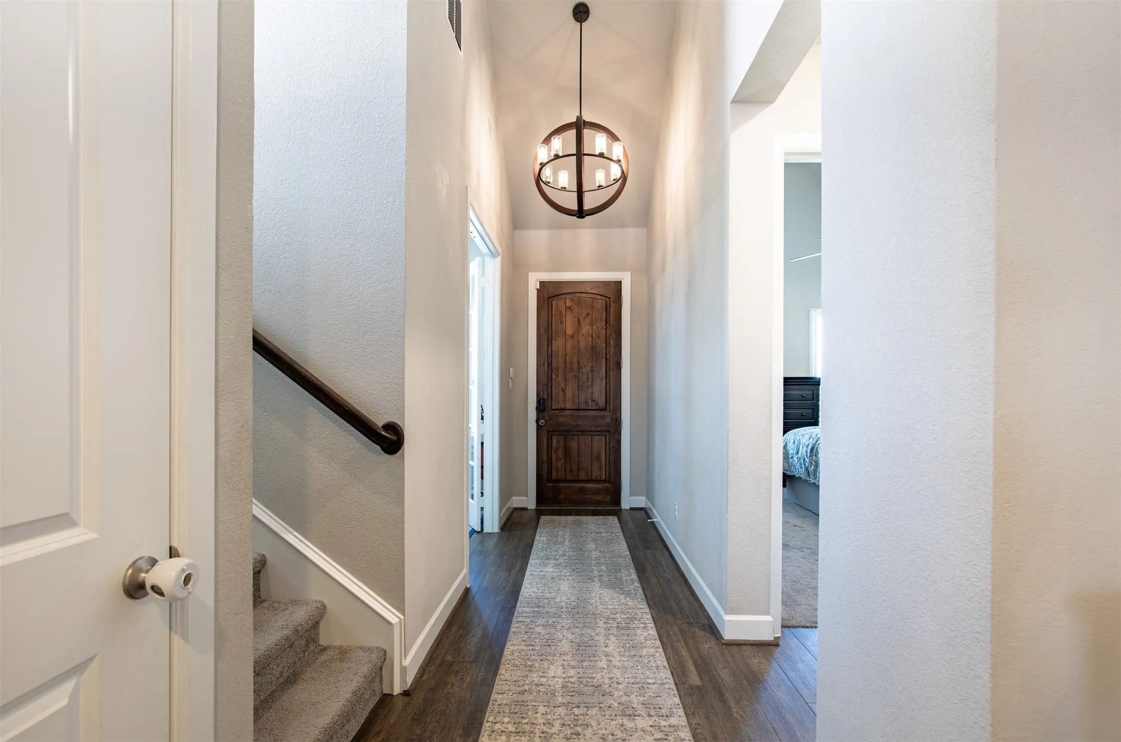 Large foyer with wood flooring and beautiful lighting.