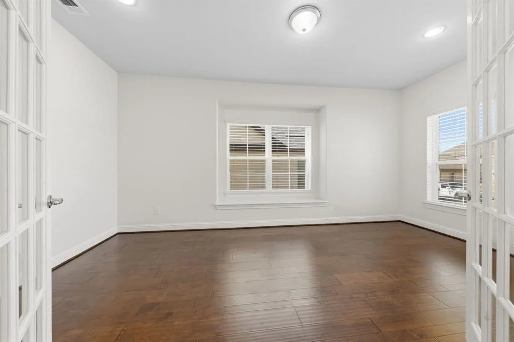 Room featuring rich wood-finish flooring, white walls, and bright recessed lighting