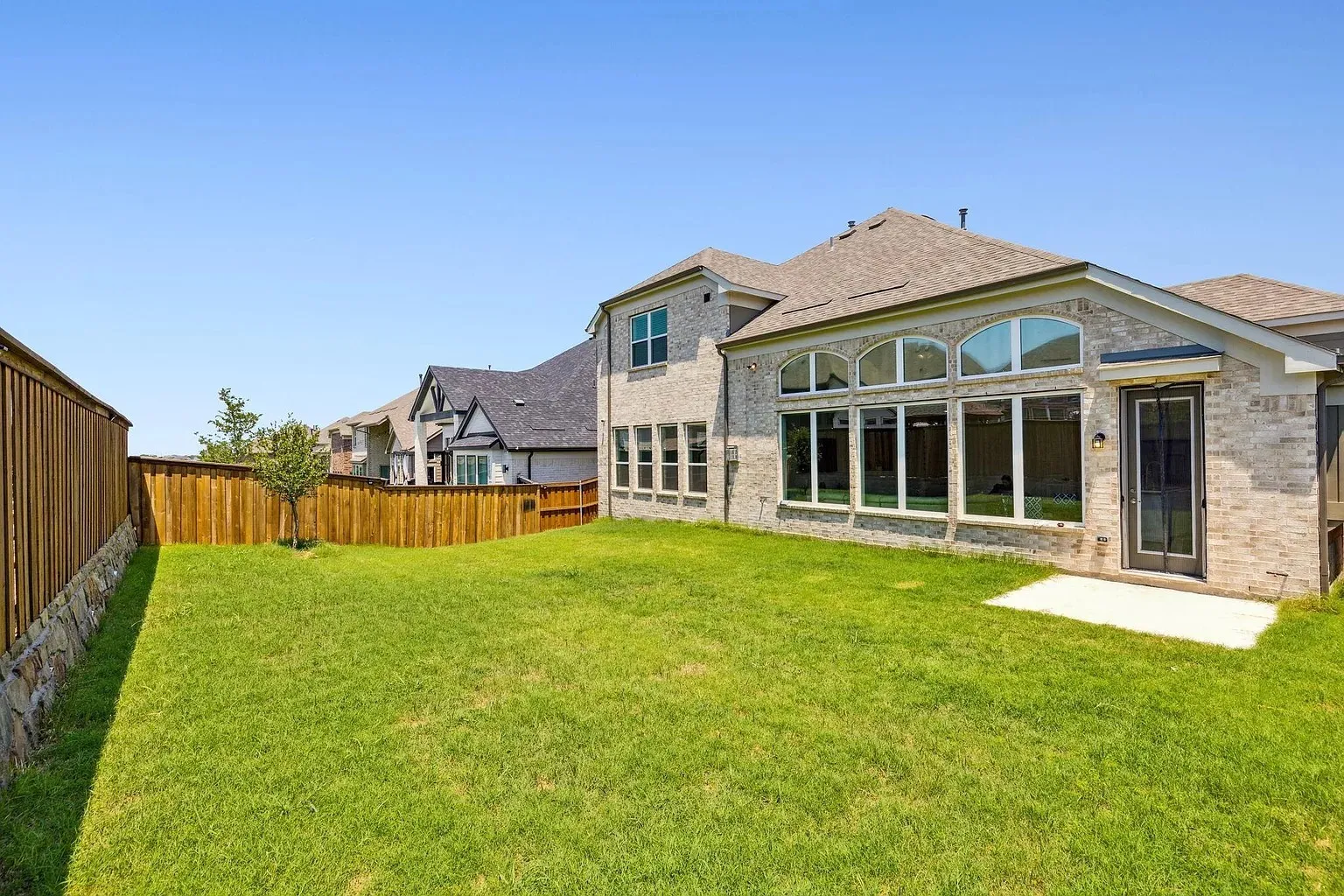 Expansive backyard with a manicured lawn, full wood fencing, and a stone retaining wall