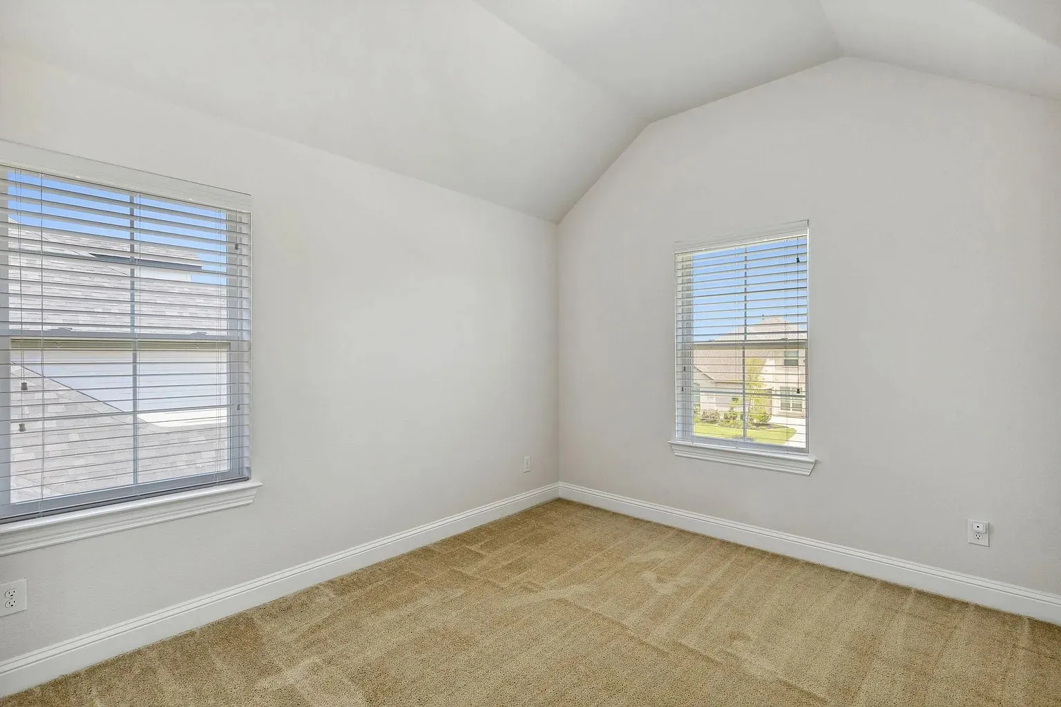 Vaulted ceiling bedroom with neutral wall paint and carpet flooring